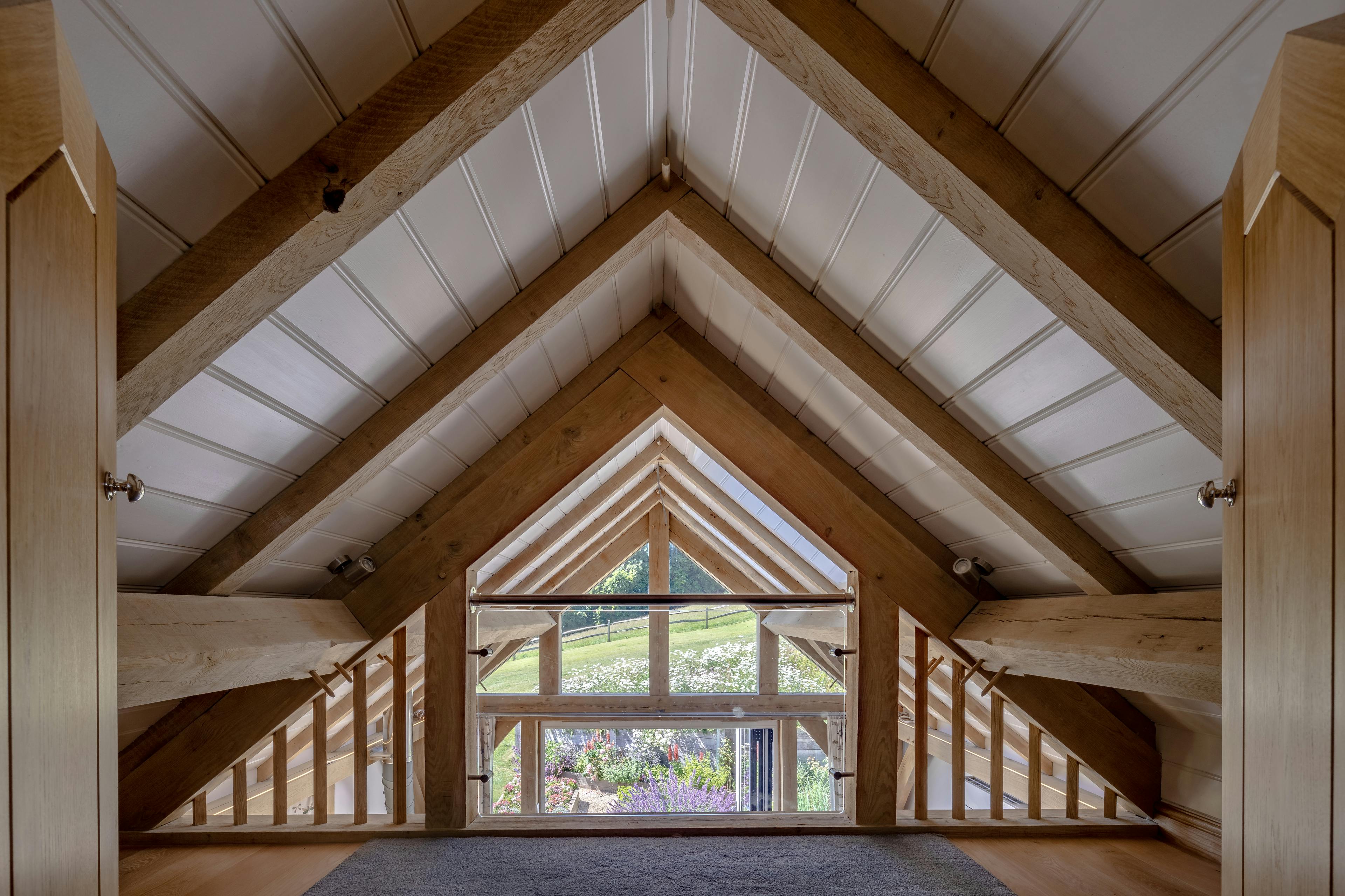 The mezzanine area inside an oak framed garden annex with white painted roof boarding