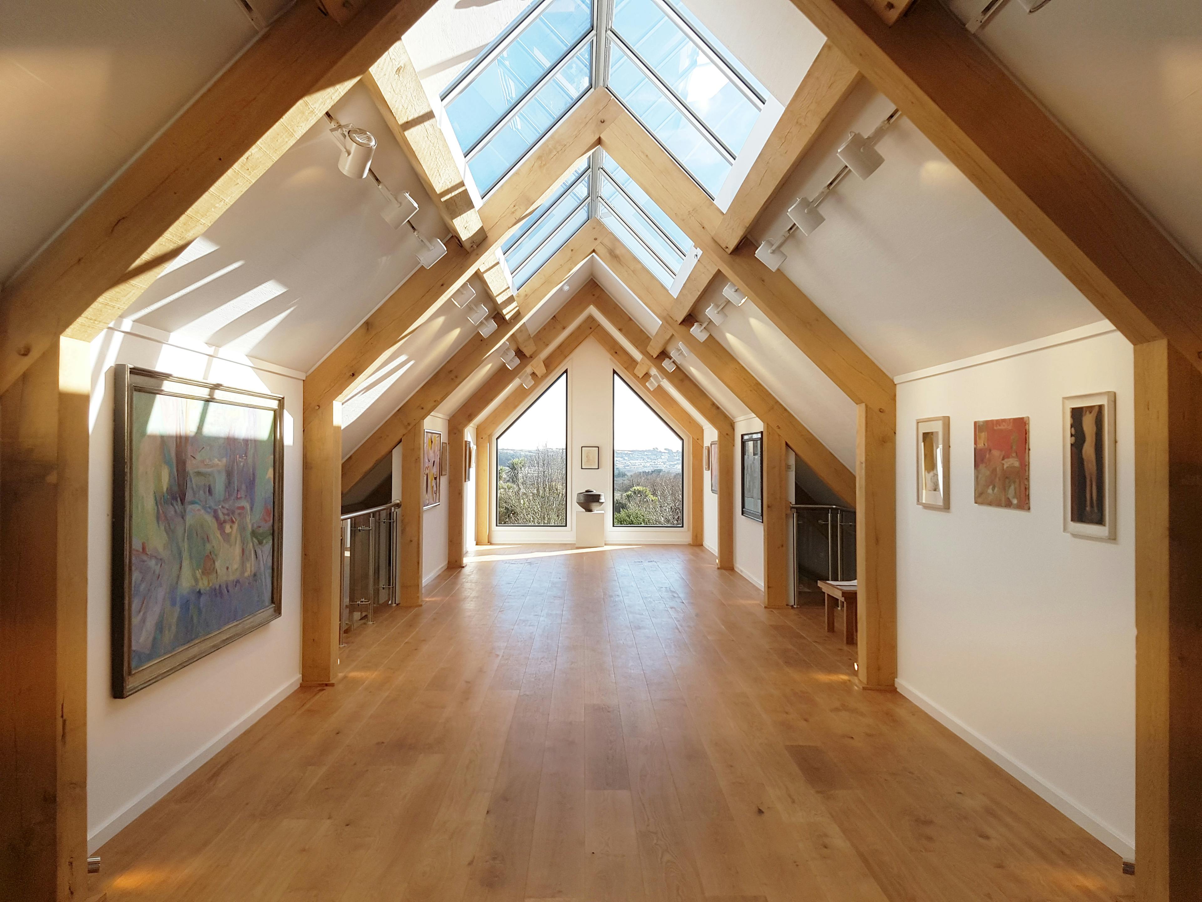 Interior view of an art gallery venue featuring an exposed structural timber frame and a roof lantern that floods the space with natural light