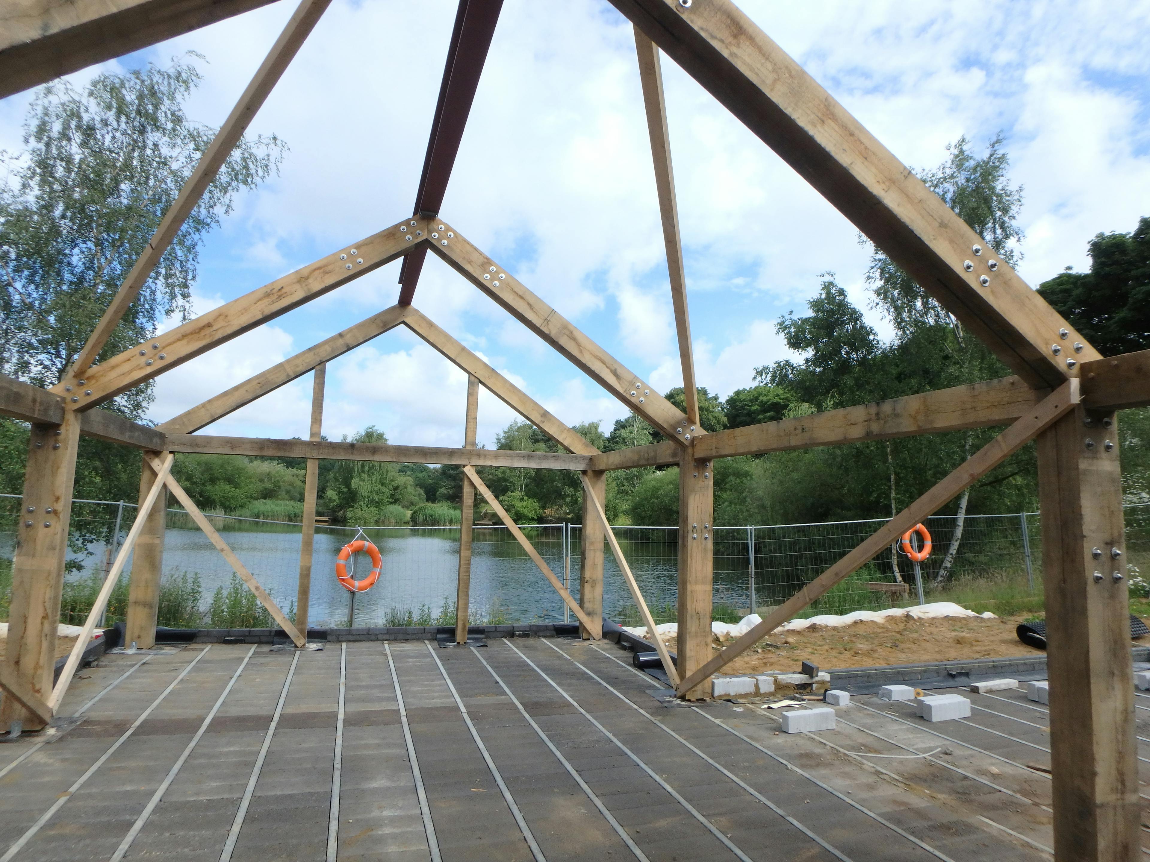 Oak frame being constructed on-site, overlooking a large lake