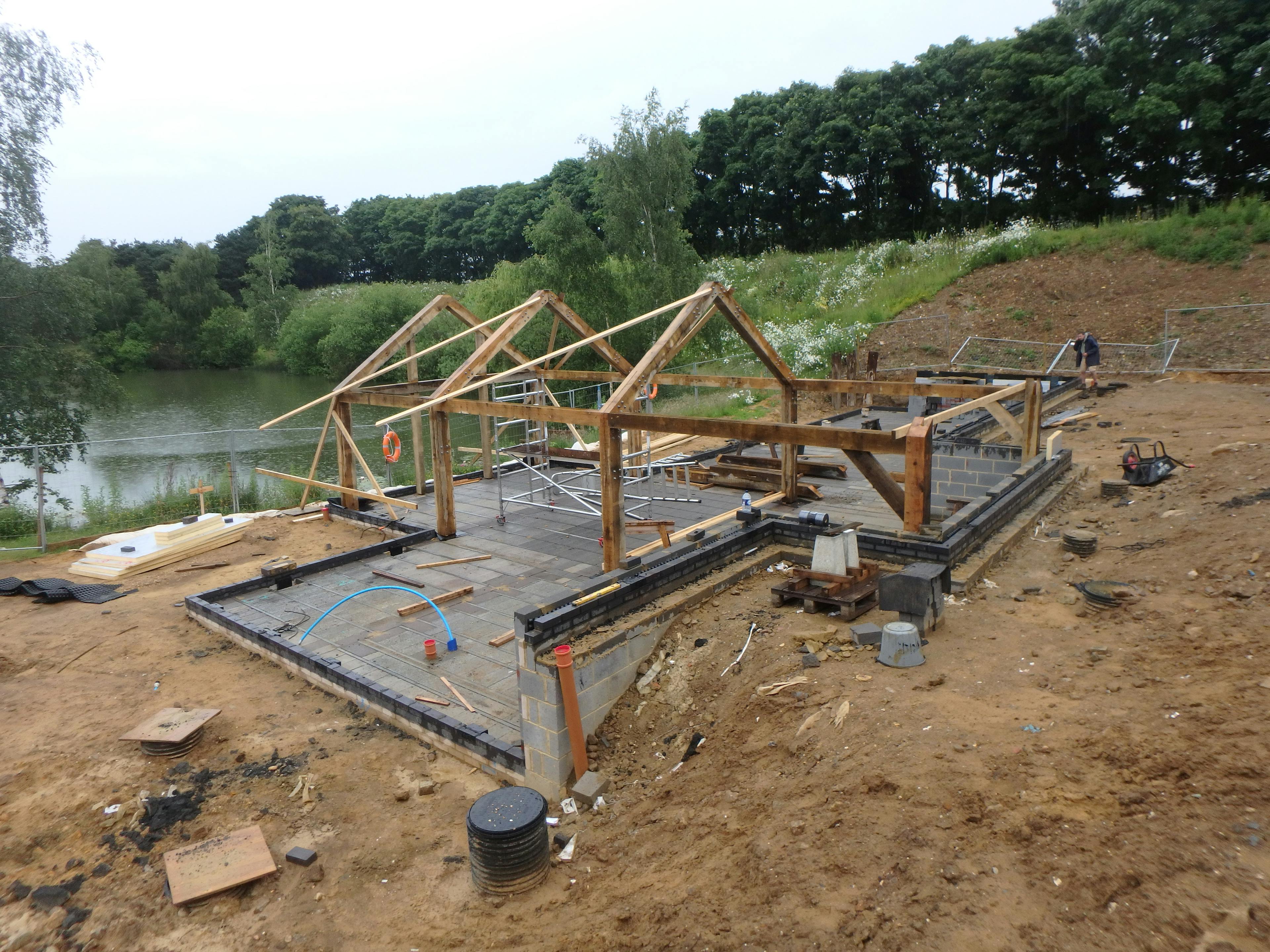 Oak-framed bungalow being installed on the shore of a natural lake