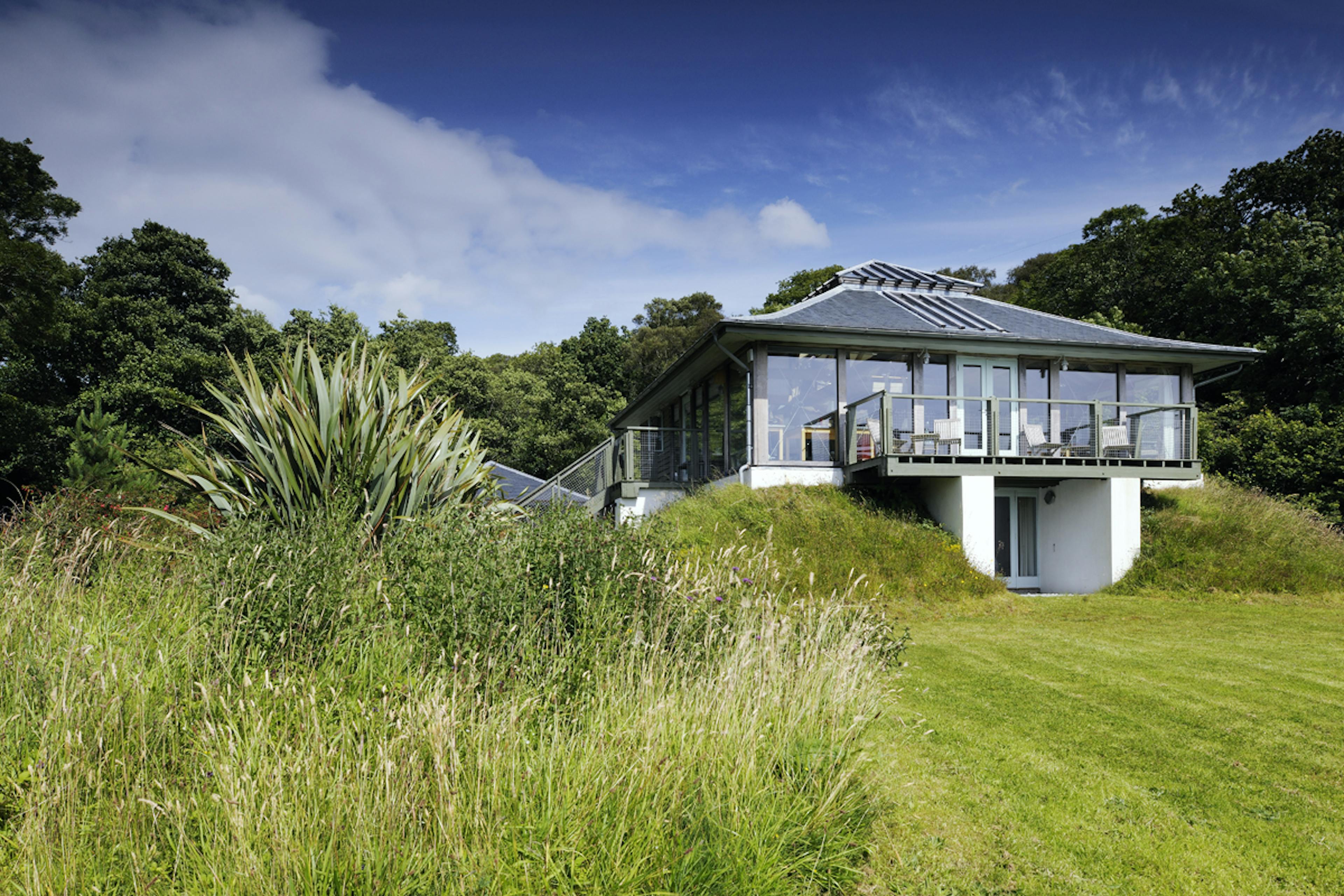 An oak framed home with oak balcony set in a green garden and lawn