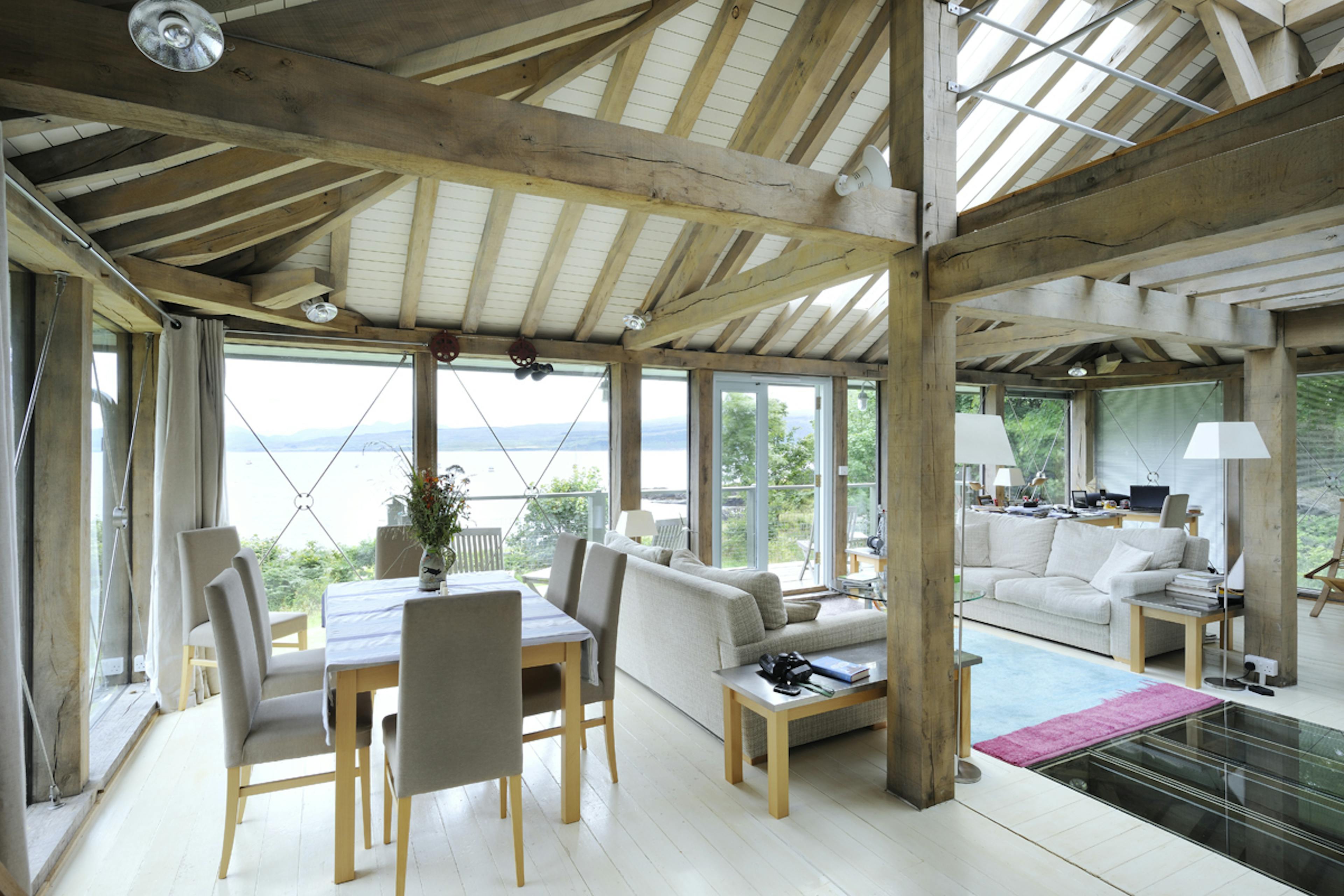 Interior view of an open-plan oak framed living space with expansive panoramic views of the coast