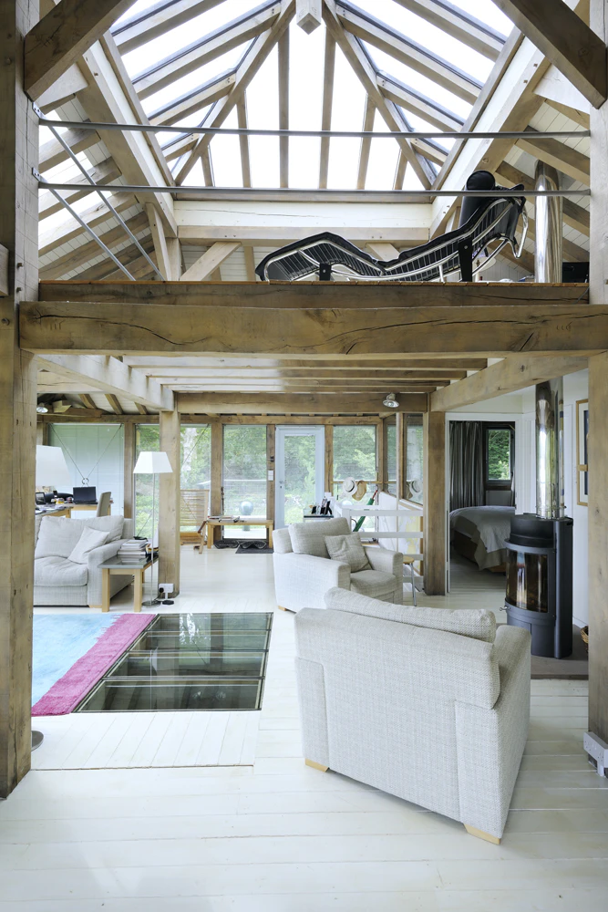 Interior view of an open-plan living space with a vaulted ceiling and a large roof lantern, flooding the room with natural light