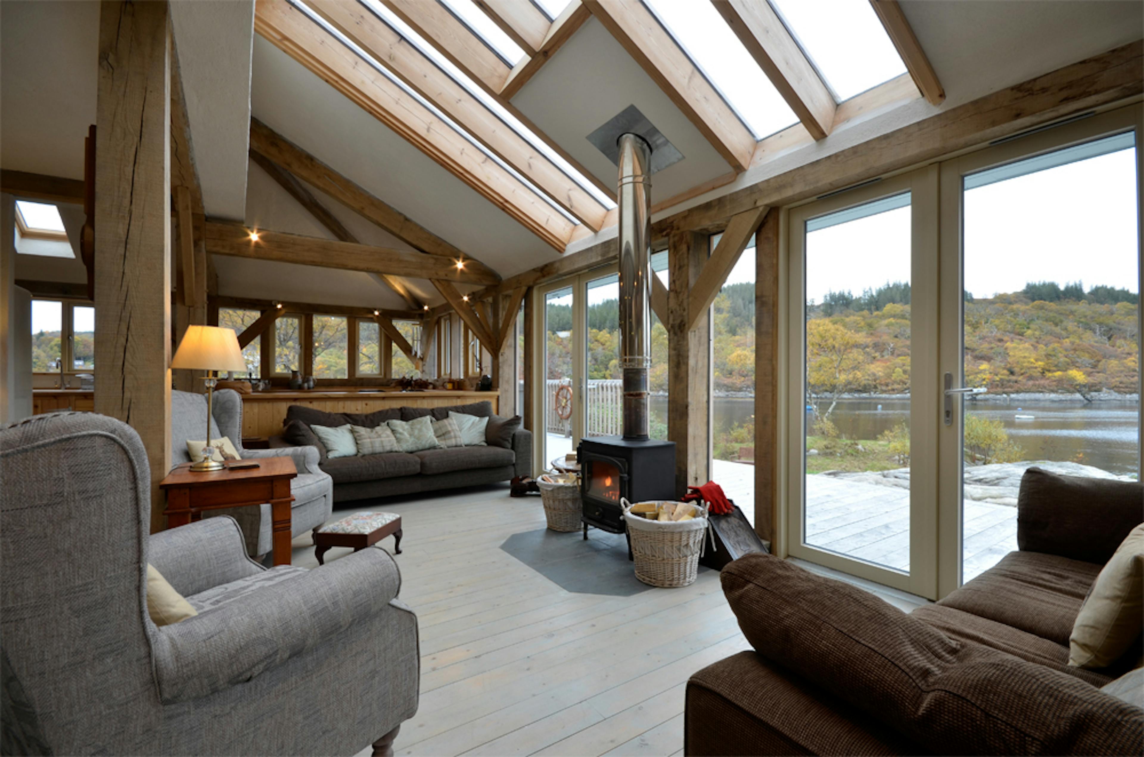 Interior view of an open-plan oak framed living space with expansive panoramic views of the loch