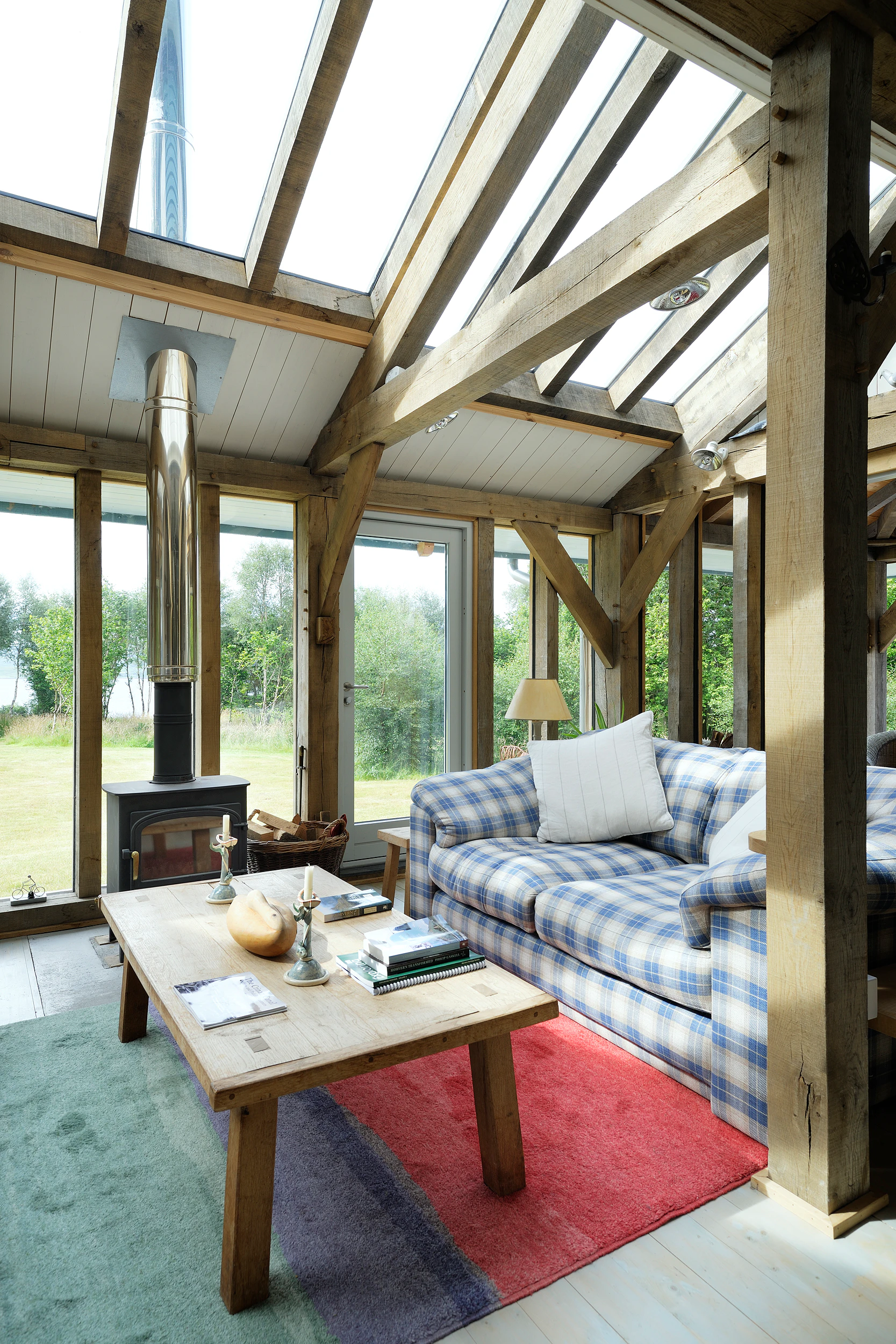 Interior view of an open-plan, oak-framed living space with a central fireplace
