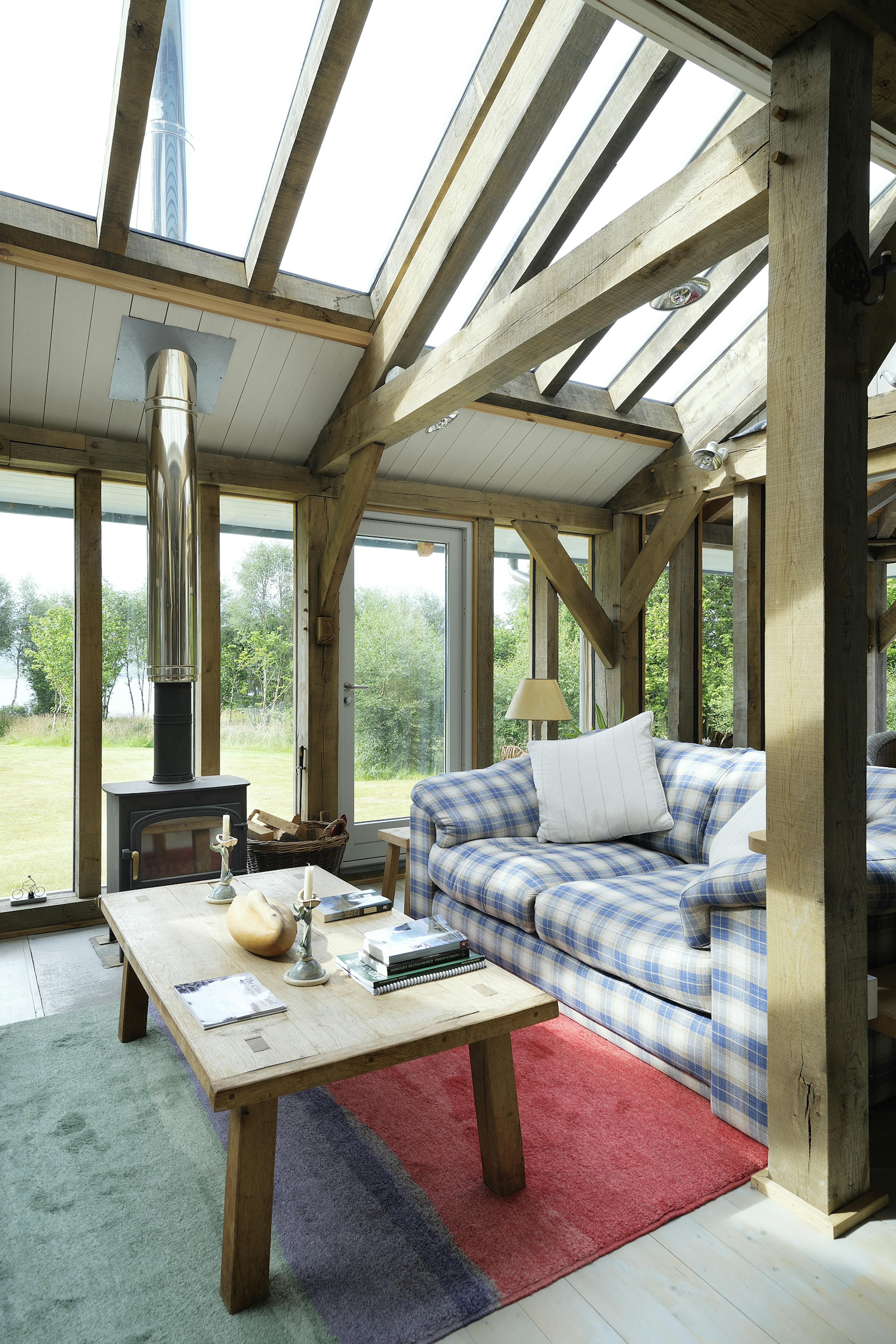 Interior view of an open-plan, oak-framed living space with a central fireplace