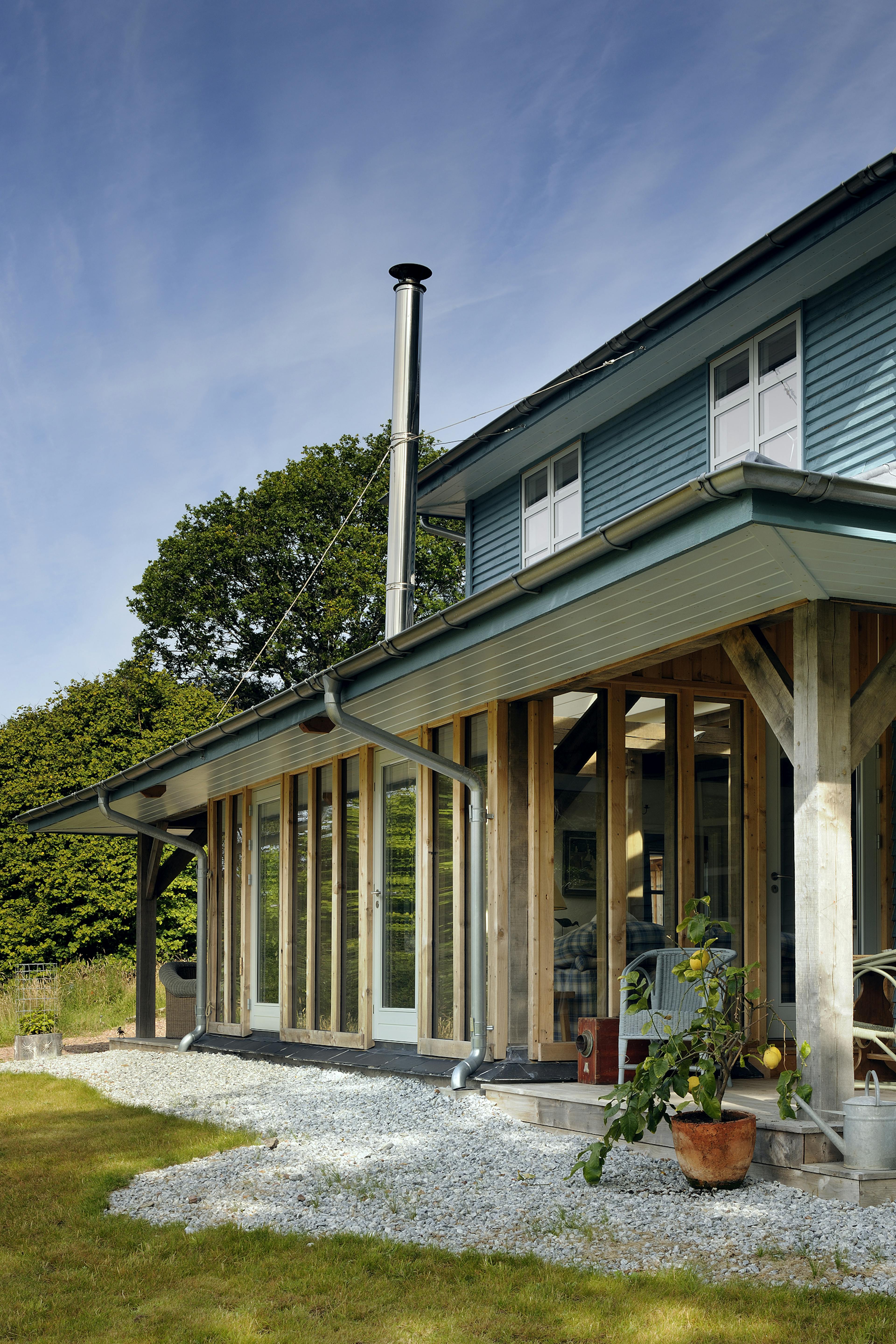 Exterior view of an oak-framed guest house featuring an overhanging roof and wrap-around veranda