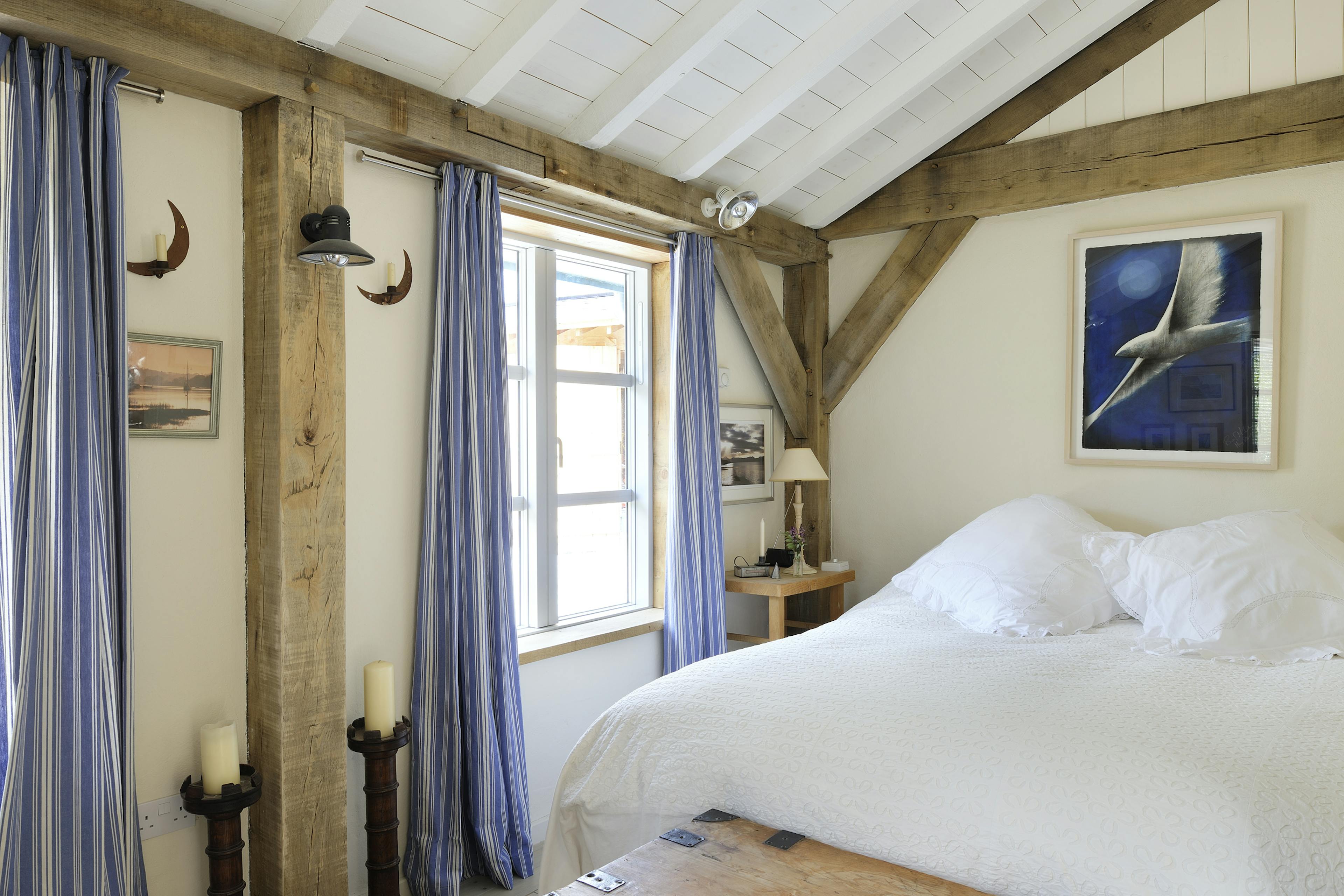 Interior view of an oak-framed bedroom with painted softwood boarding