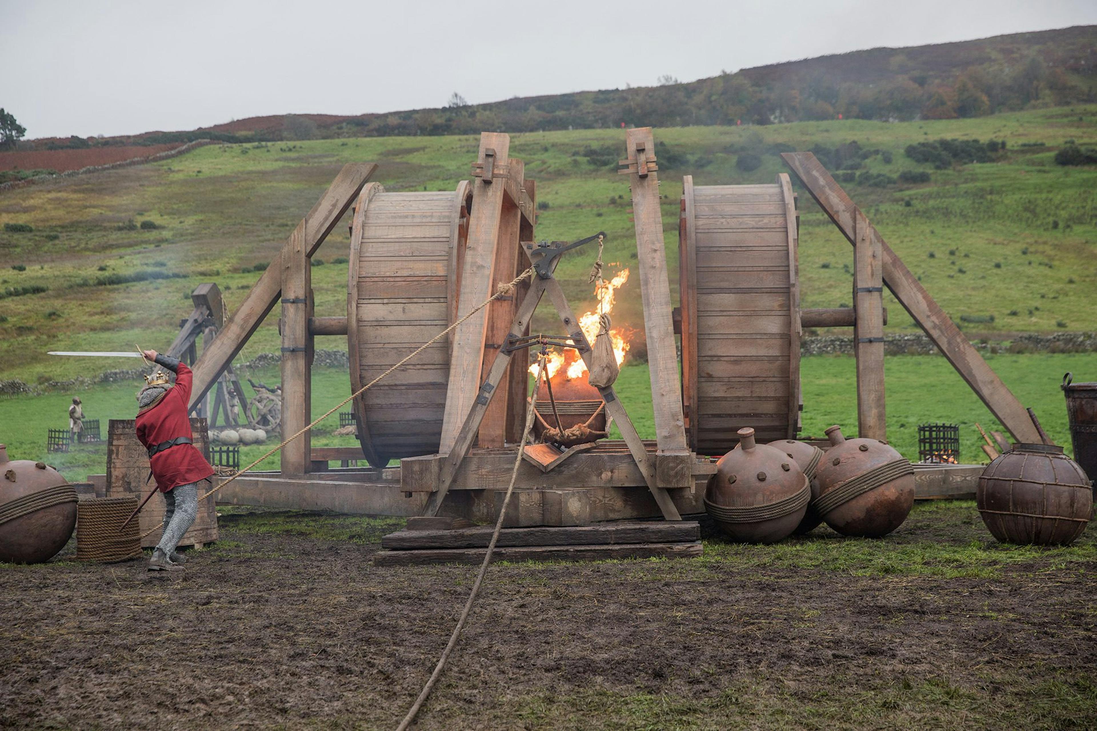 A wooden trebuchet with a flaming missile on a film set for netflix The Outlaw King