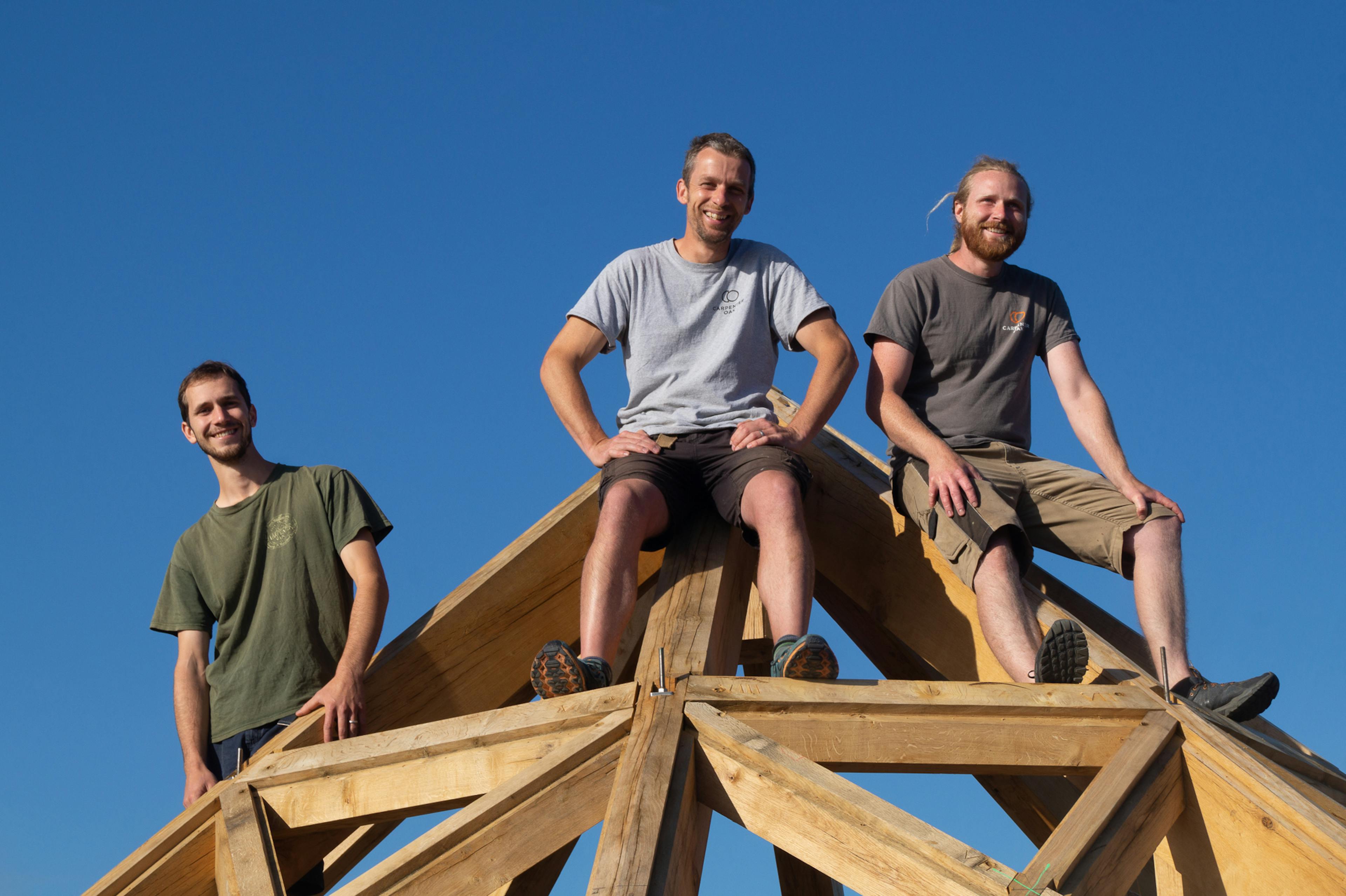 three carpenters sit on top of a an octagonal oak roof structure