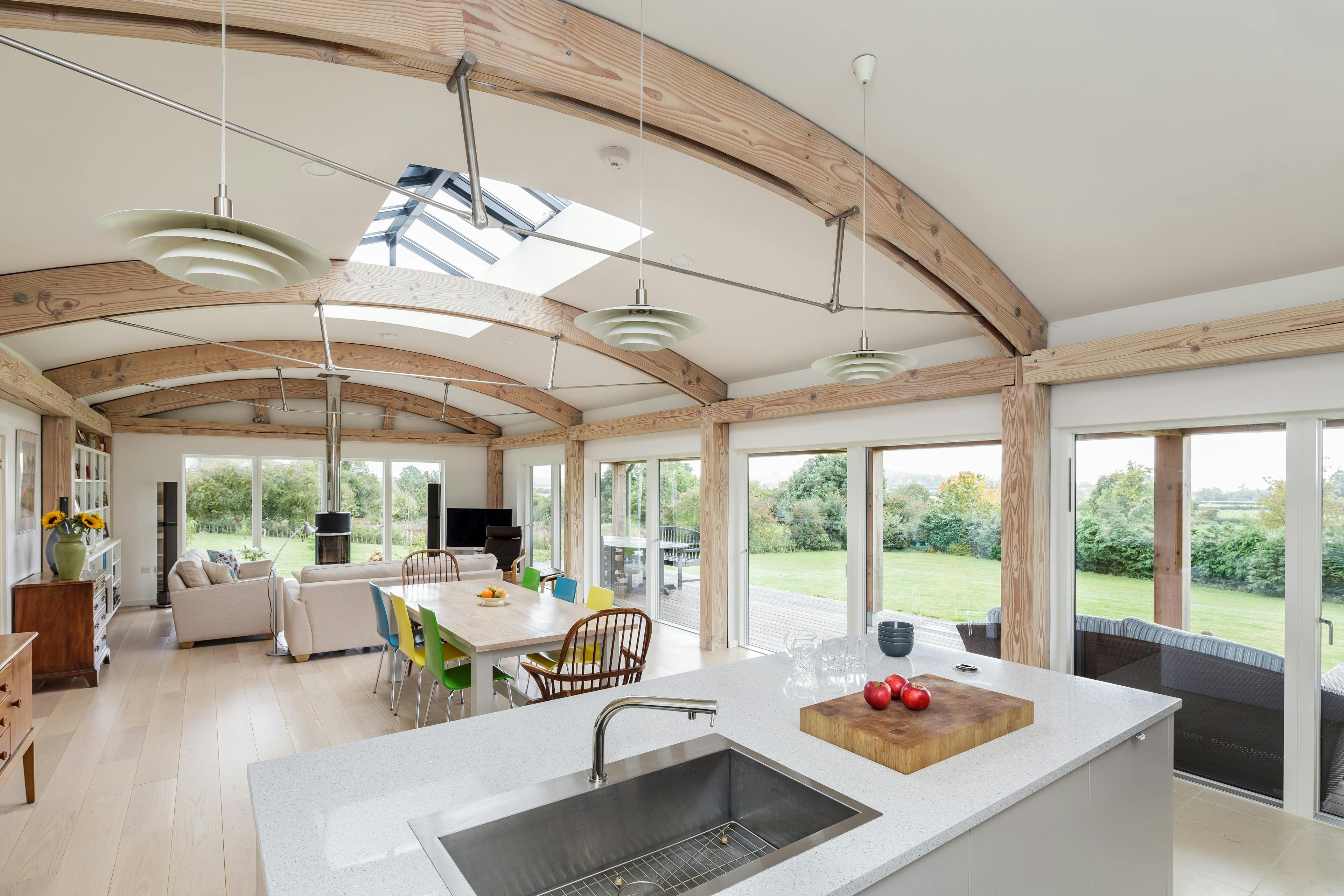 Interior view of a contemporary open-plan family home featuring unique exposed curved Douglas fir beams