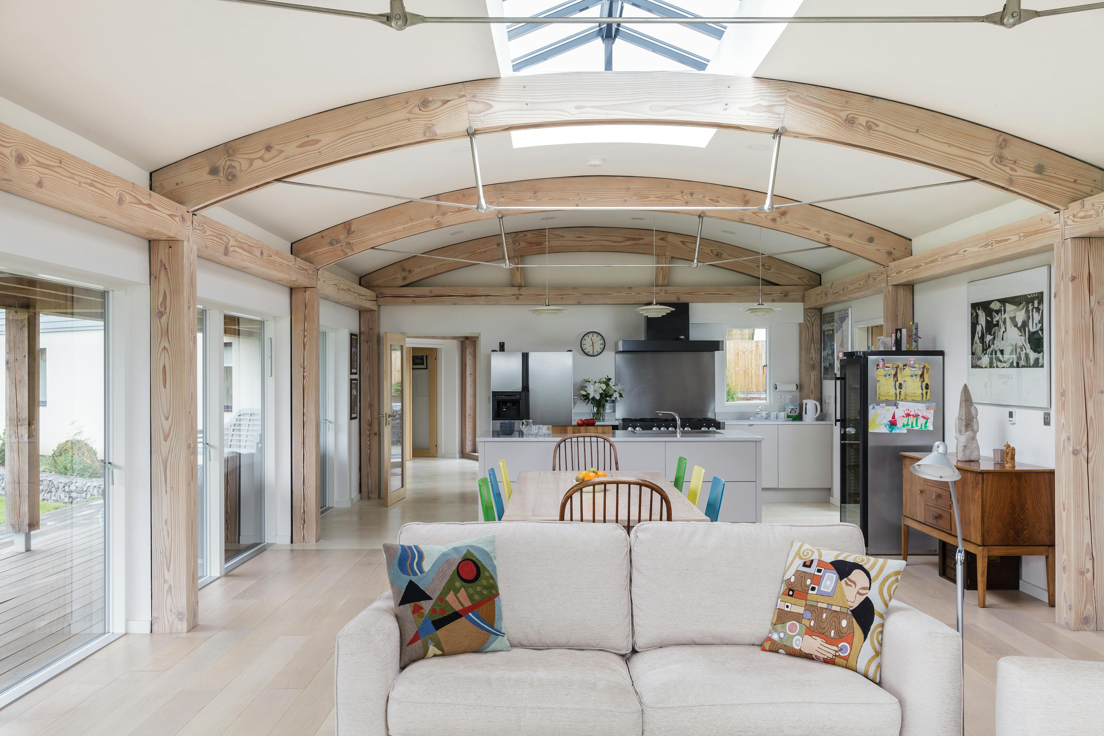 Image of an open-plan living space with curved Douglas fir beams and steel connections