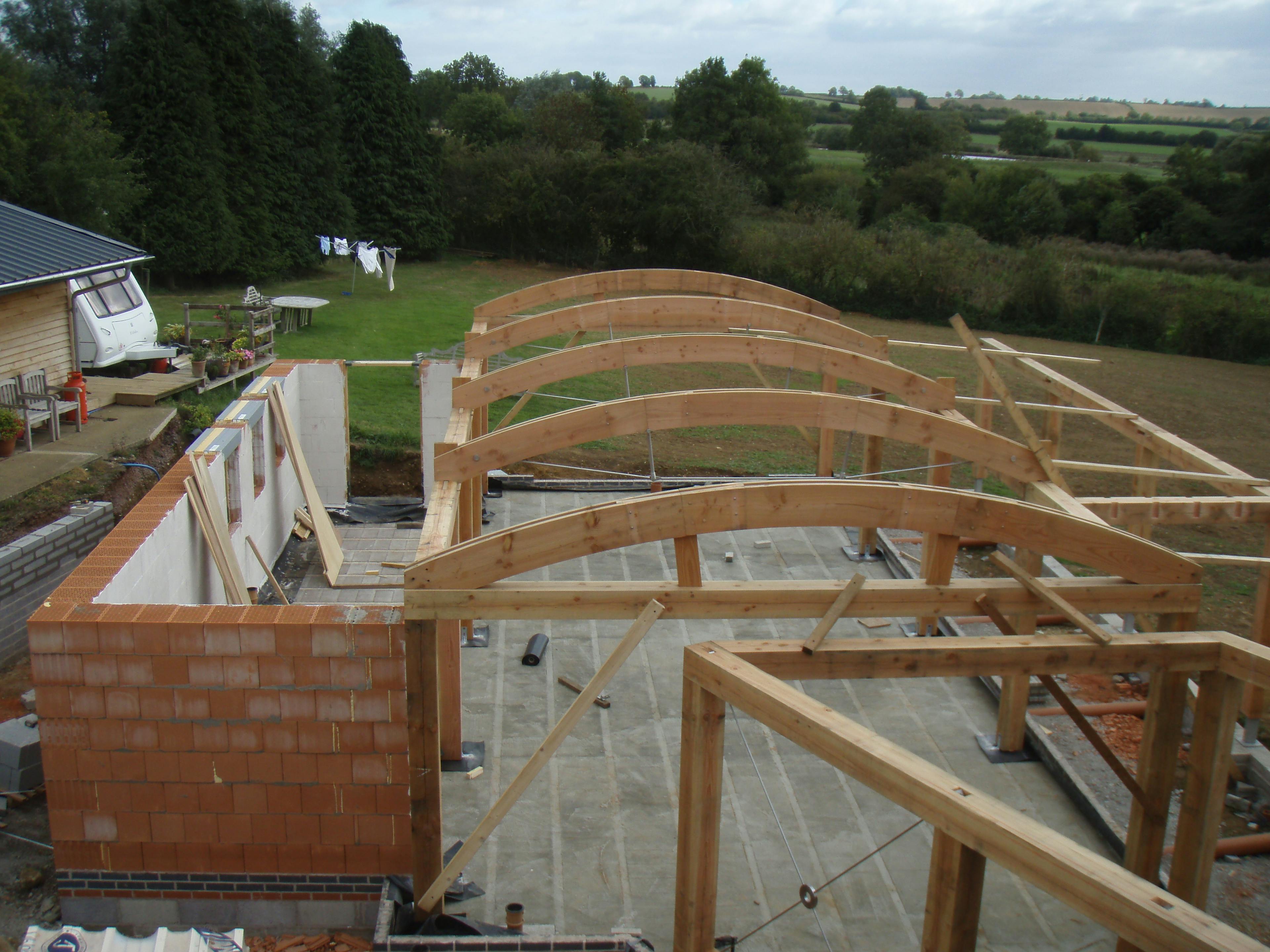 On-site assembly of a structural timber frame featuring distinctive curved roof beams