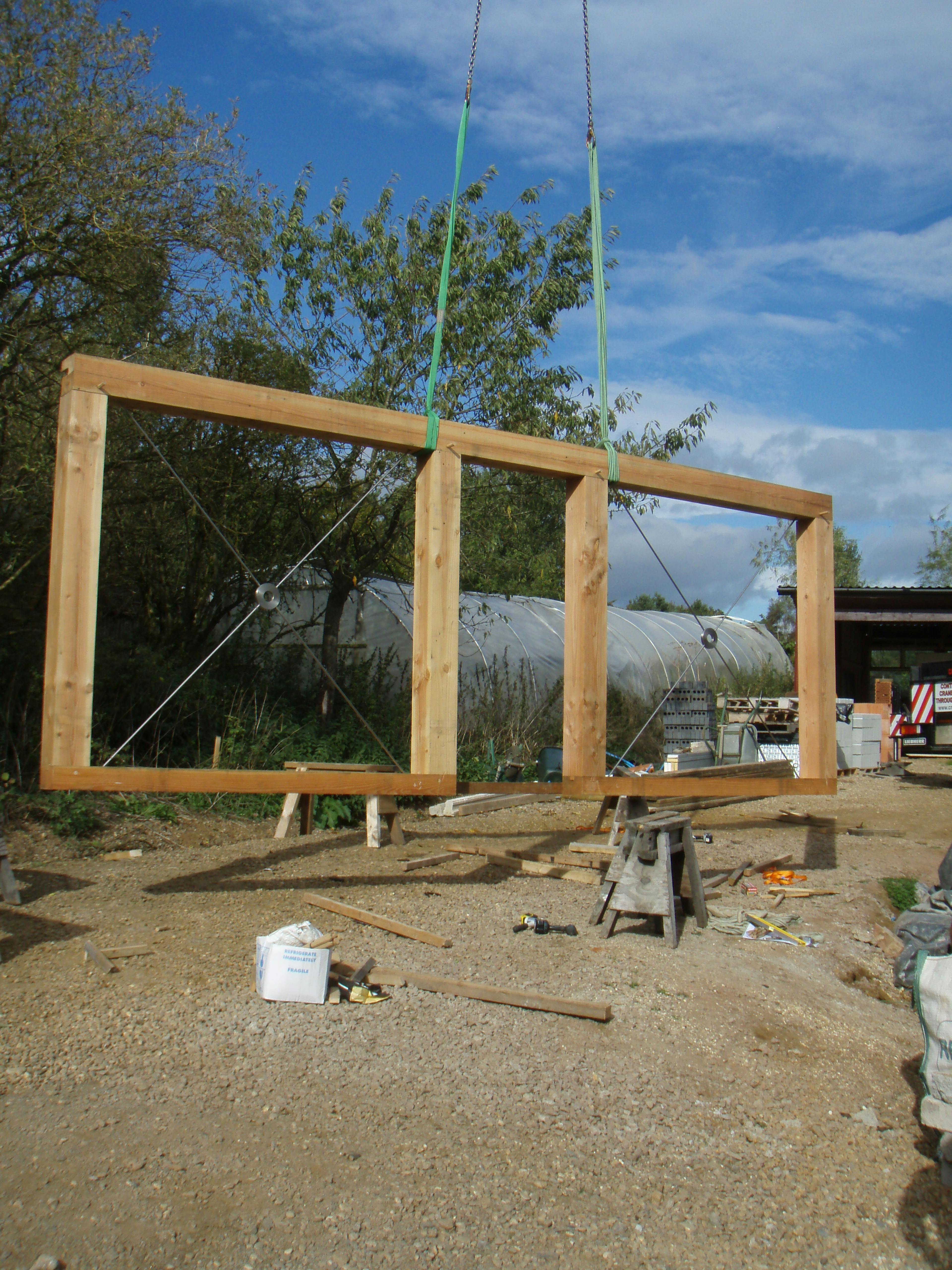 Installation of a wall section in a structural timber-framed family home, featuring exposed steel connections