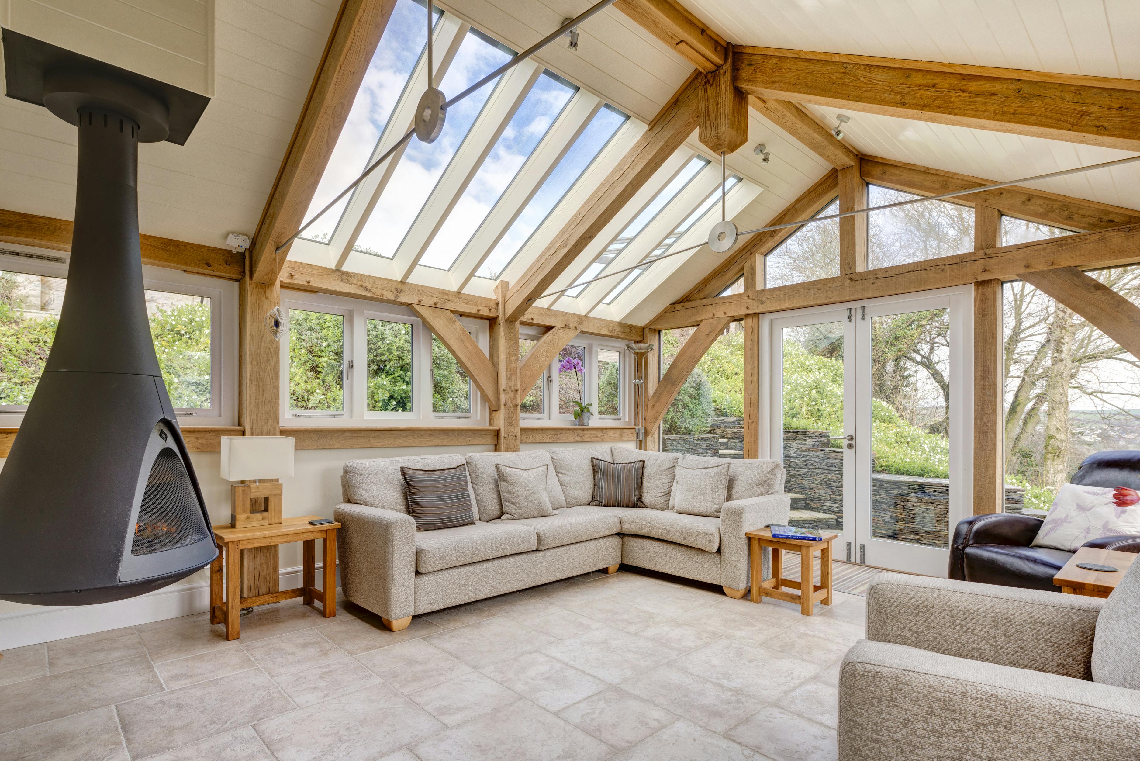 An oak framed living room with steel tie rods and a black log burner