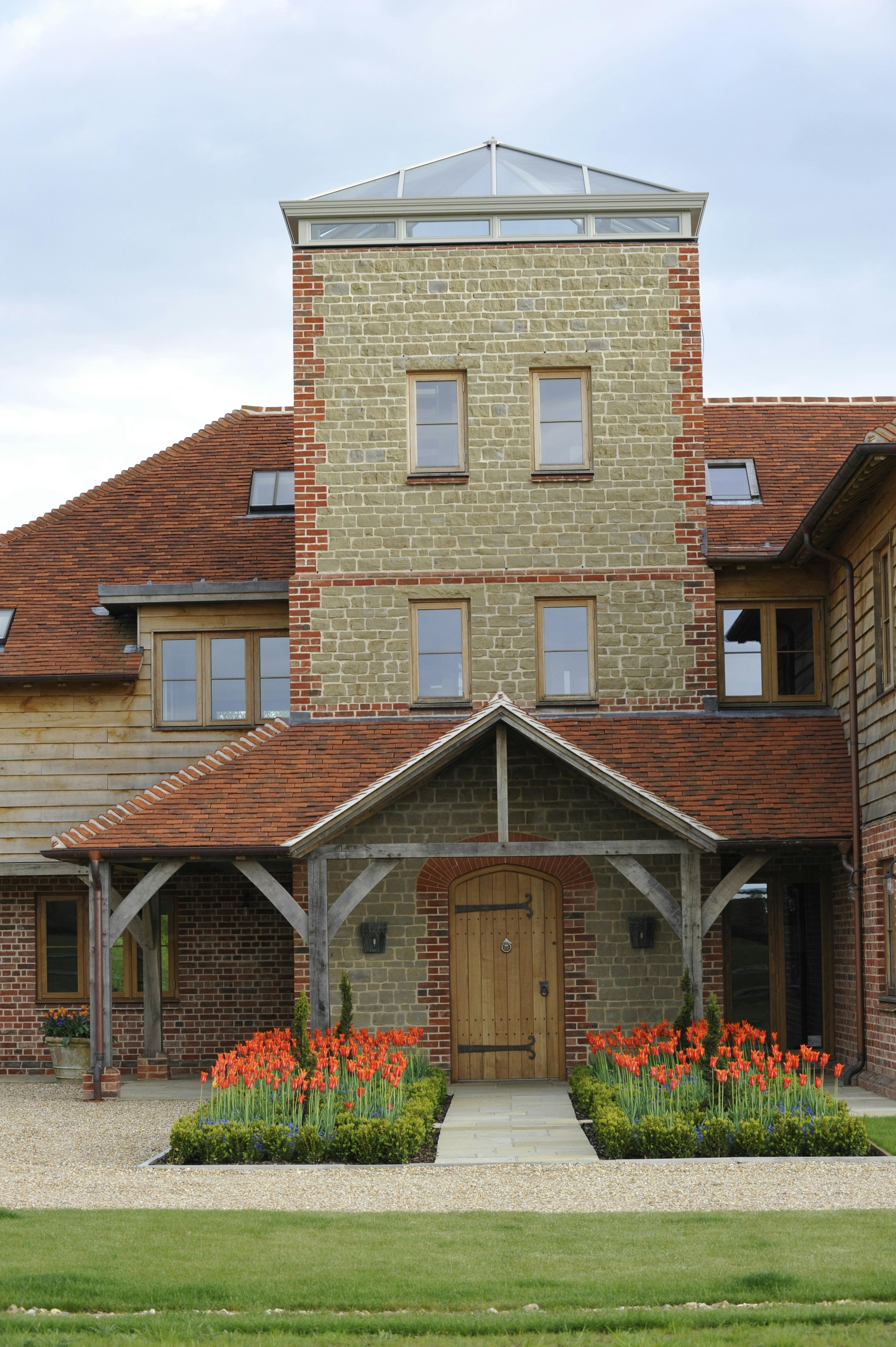 Entrance to a large-scale timber-framed family home featuring a three-story, fully glazed viewing tower