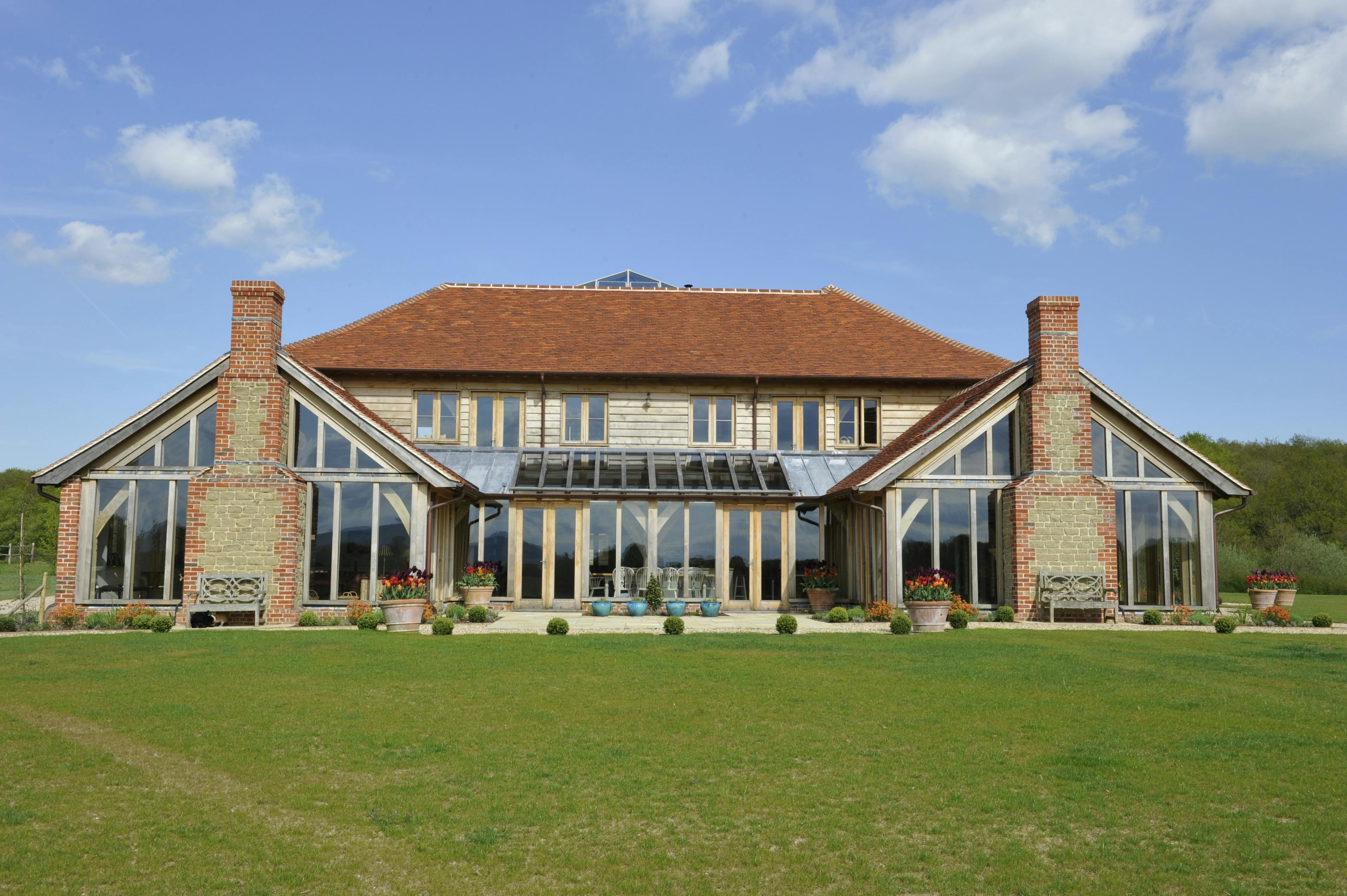 Exterior view of a farmhouse-style country home featuring two single-story barn-style structures with fully glazed gable ends