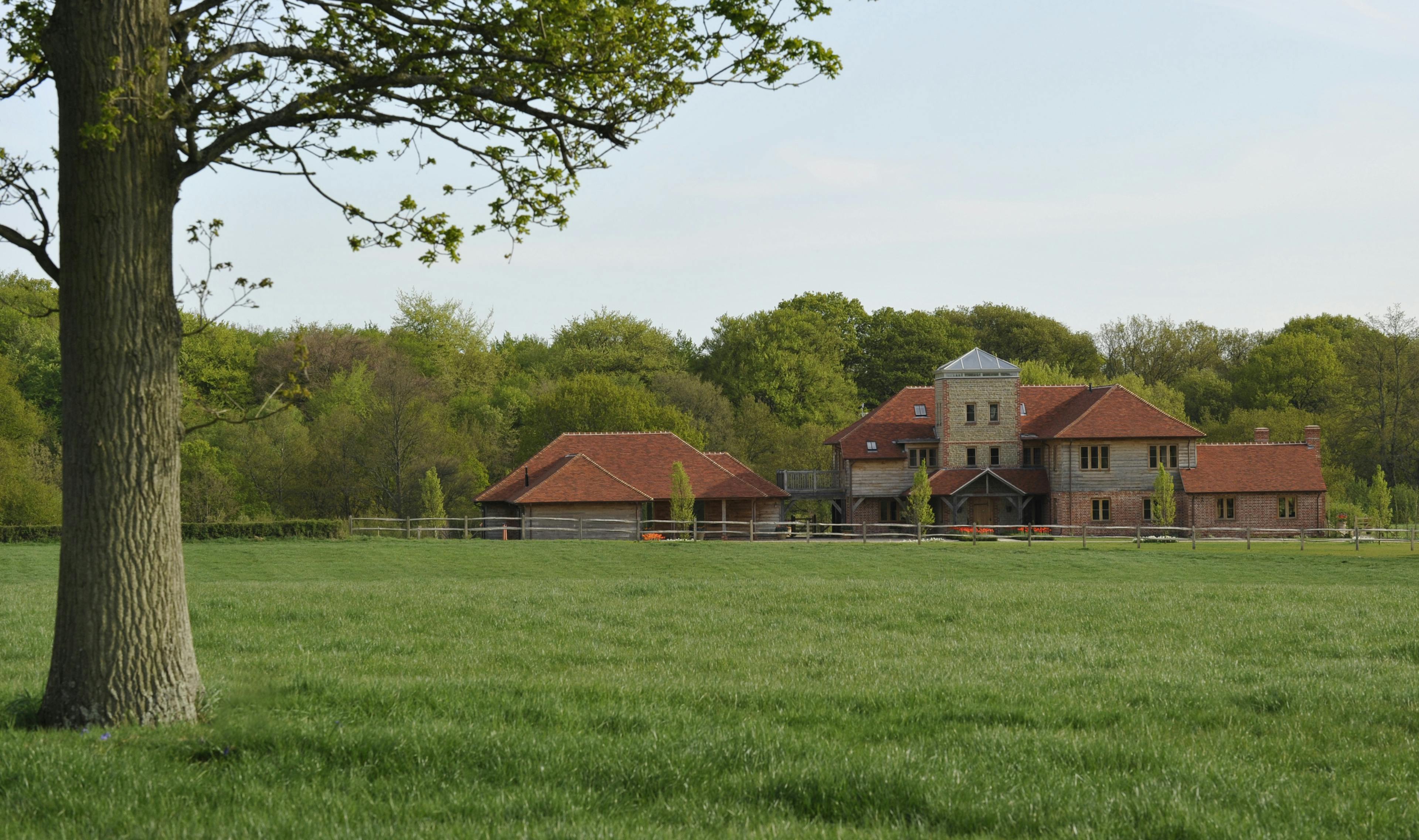 Exterior view of an expansive oak-framed family home with multiple levels and a unique central viewing tower