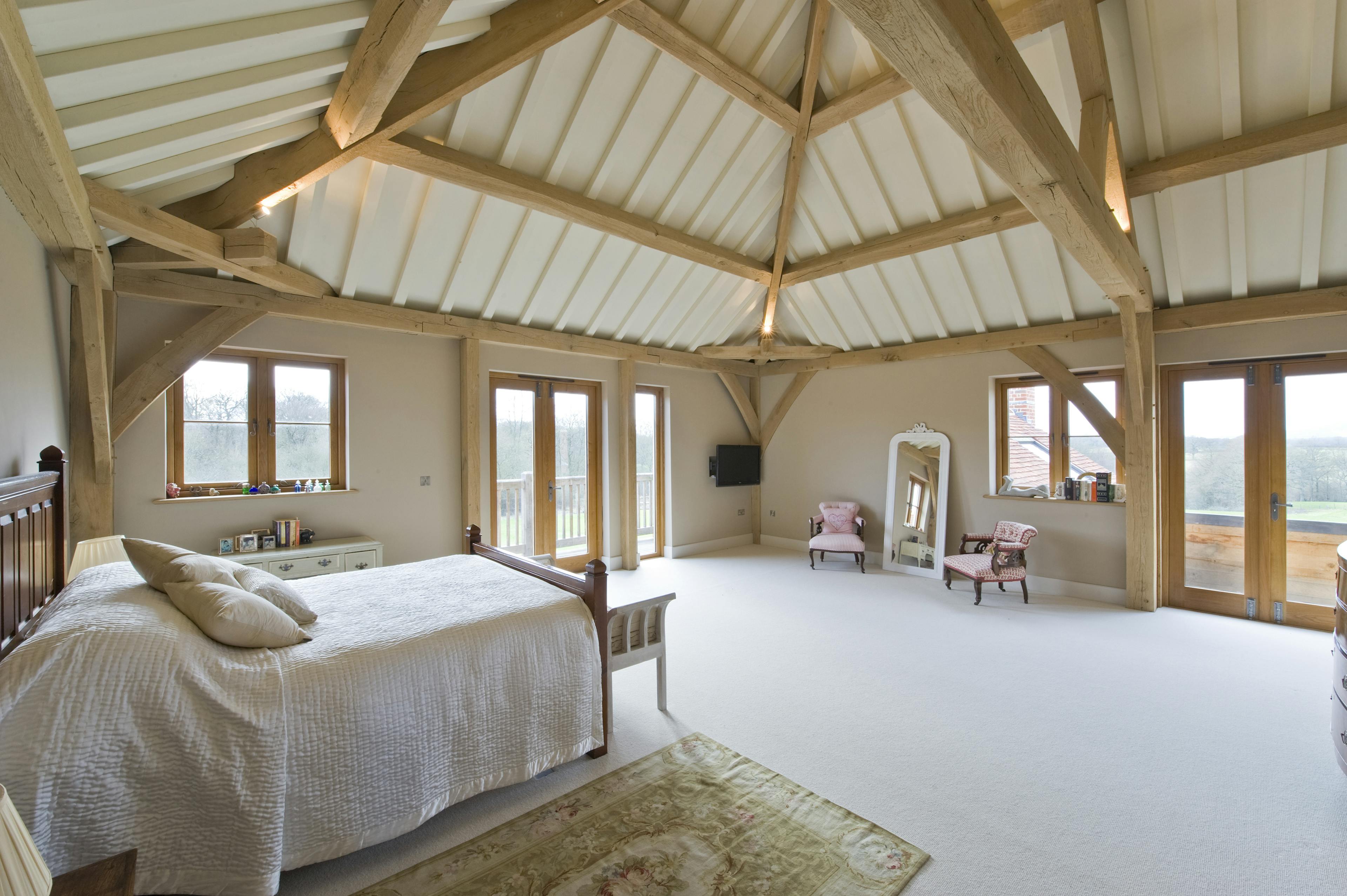 Interior view of an oak-framed bedroom offering panoramic countryside views