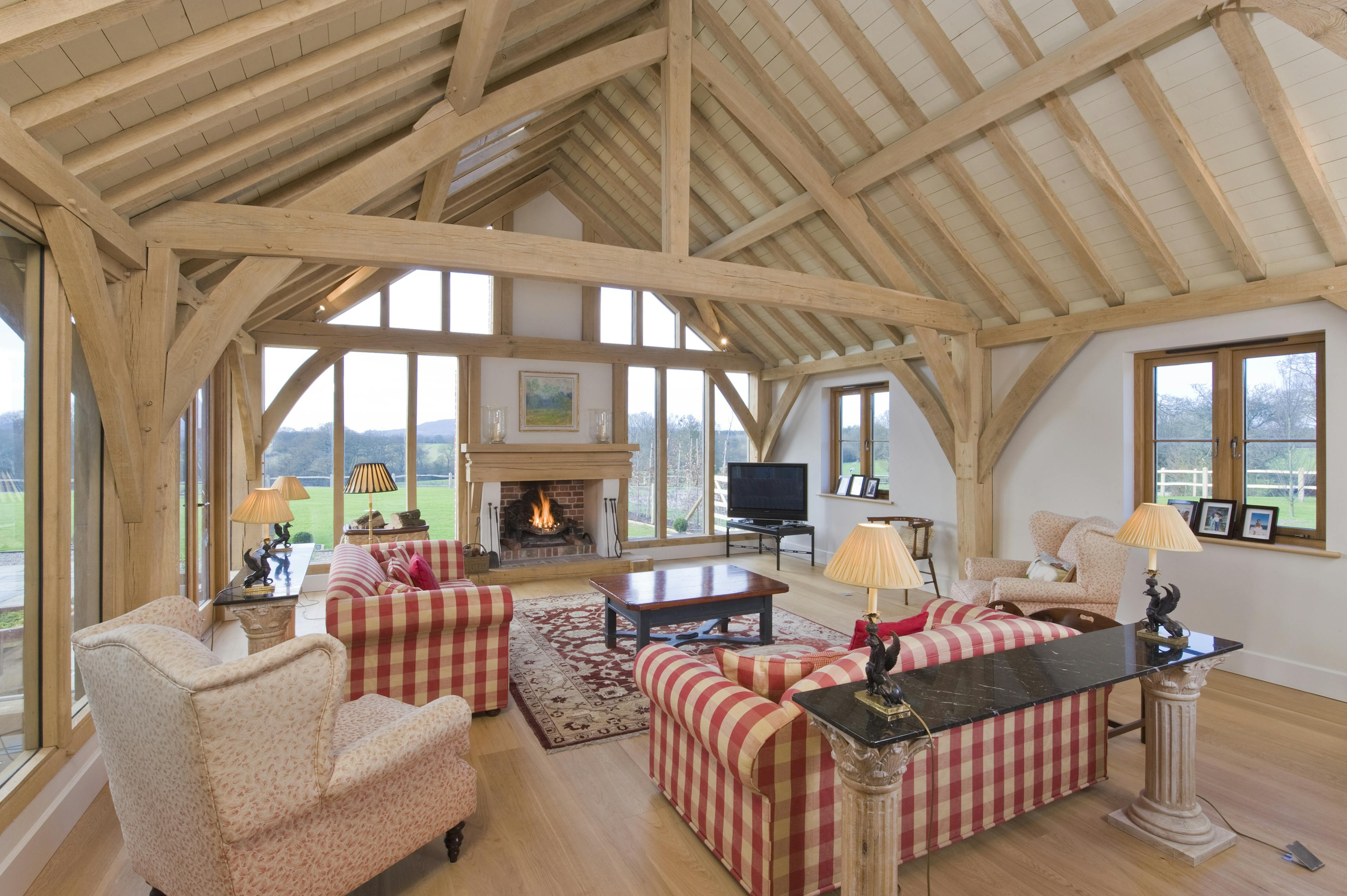 Interior view of an oak-framed barn-style space featuring a glazed gable end and a built-in fireplace
