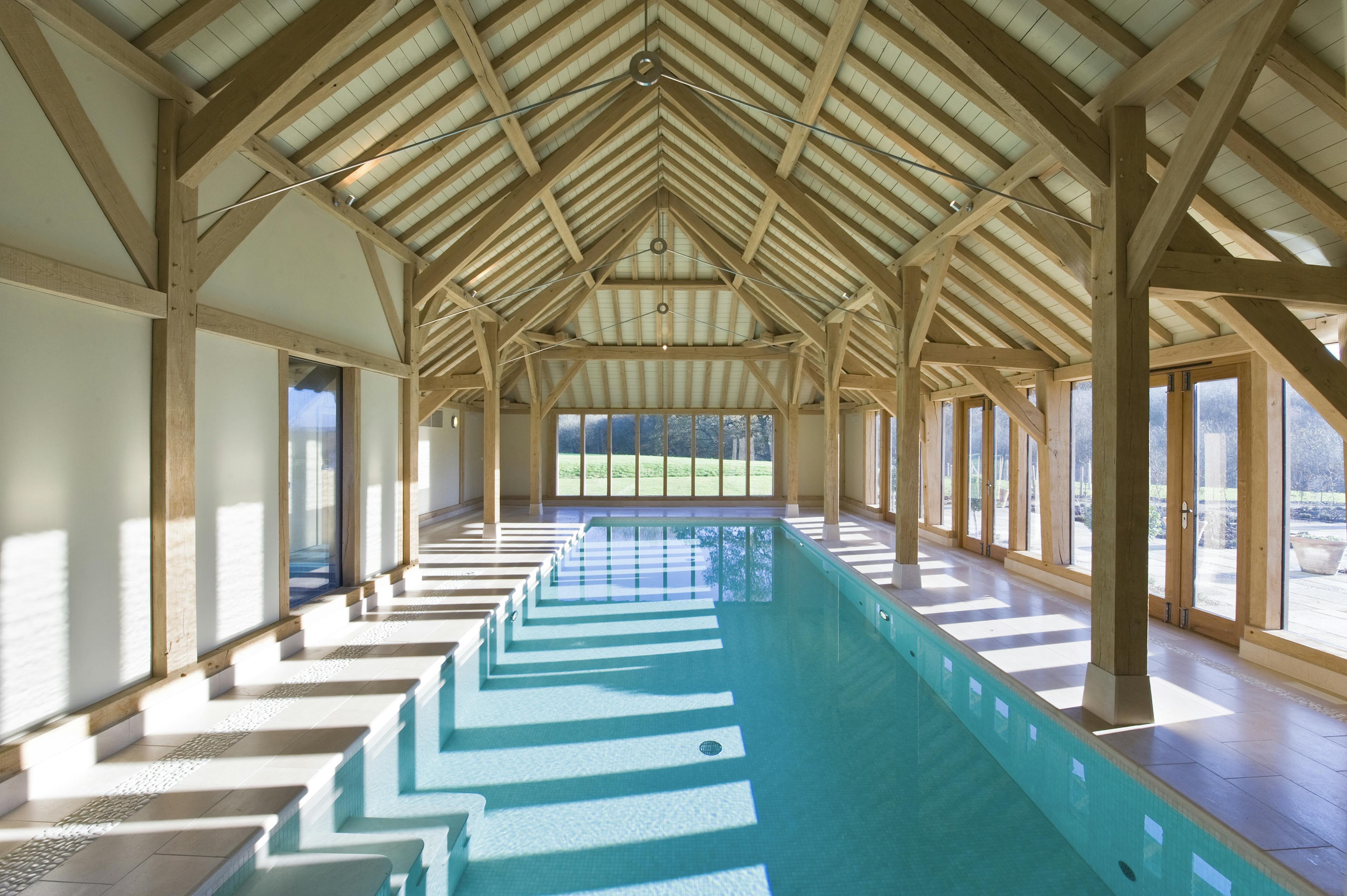 Contemporary swimming pool with a vaulted ceiling supported by oak-framed trusses with steel connections