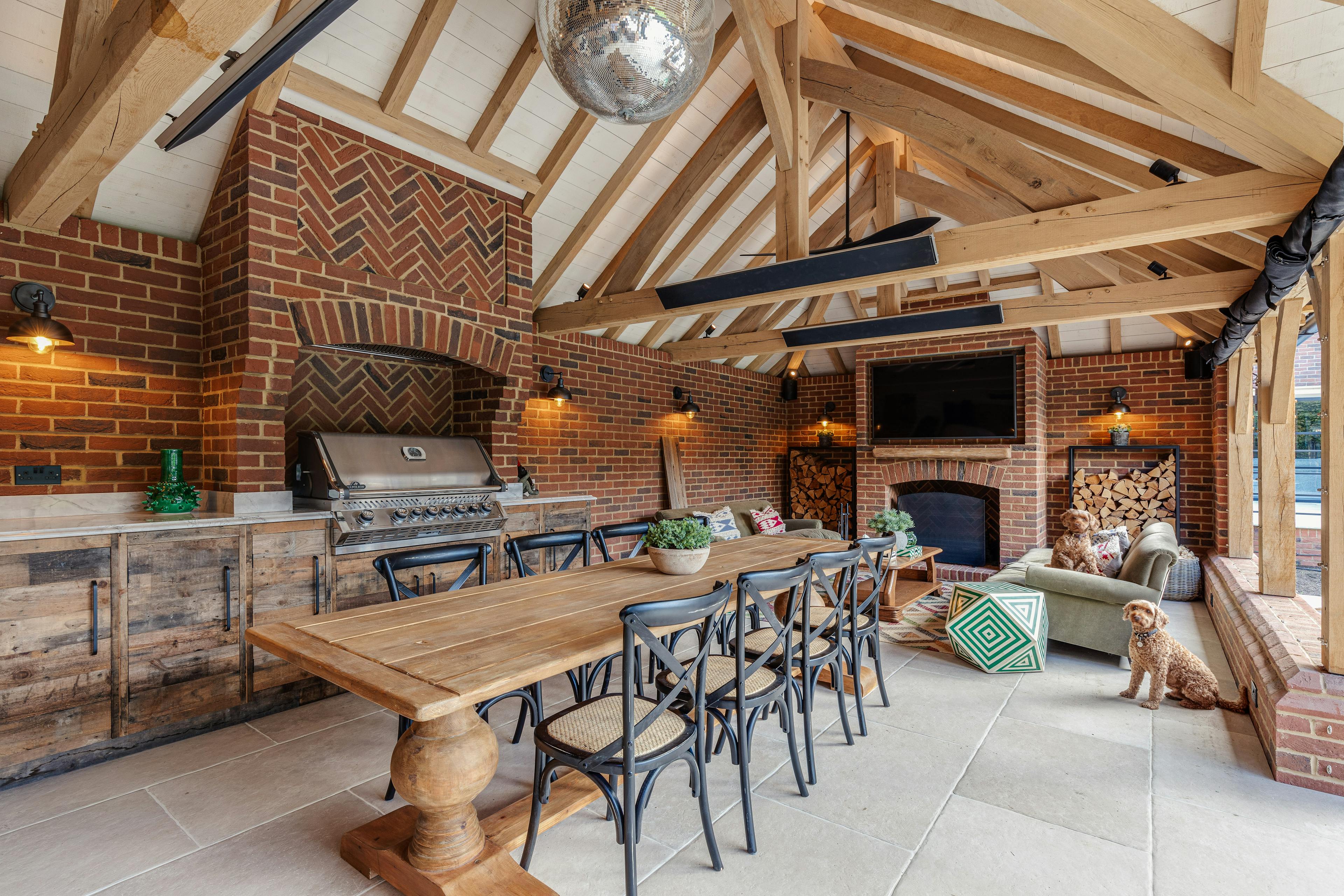 An oak frame outdoor bar and kitchen with dining and sitting area, fireplace and bbq