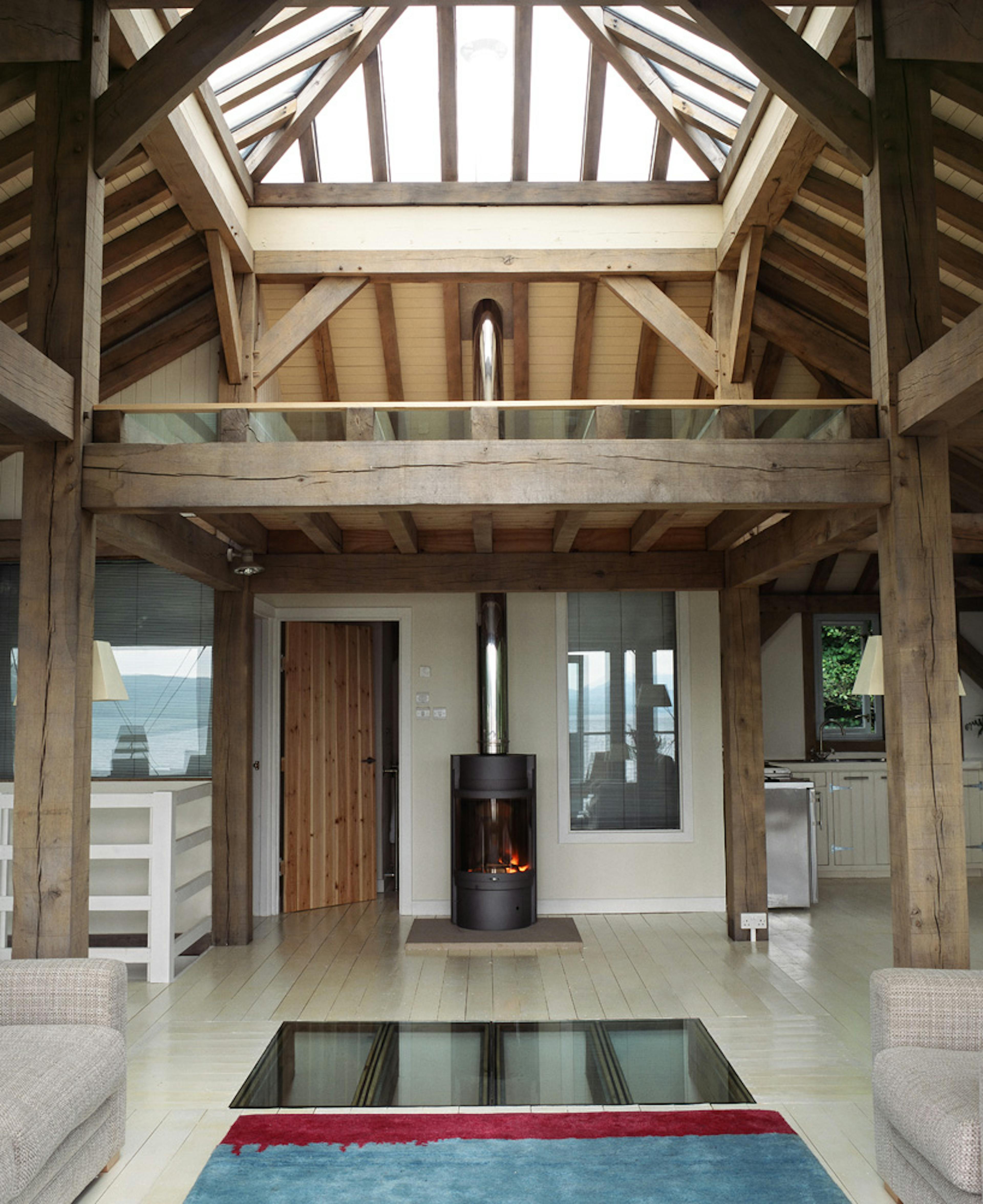 Interior view of an open-plan living room with a mezzanine and a large roof lantern, flooding the space with natural light