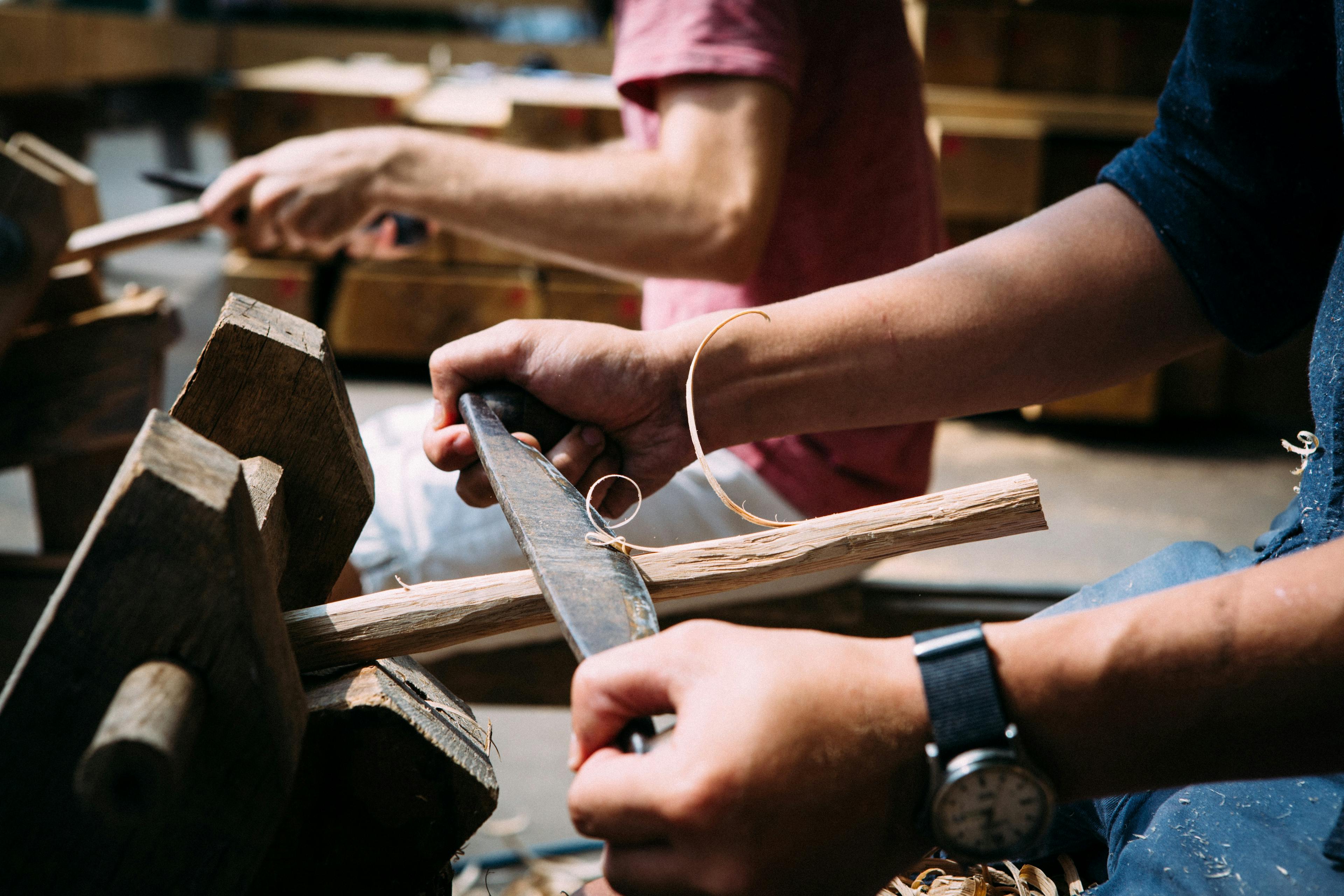 Carpenters hand craft wooden pegs for structural timber frames in a workshop