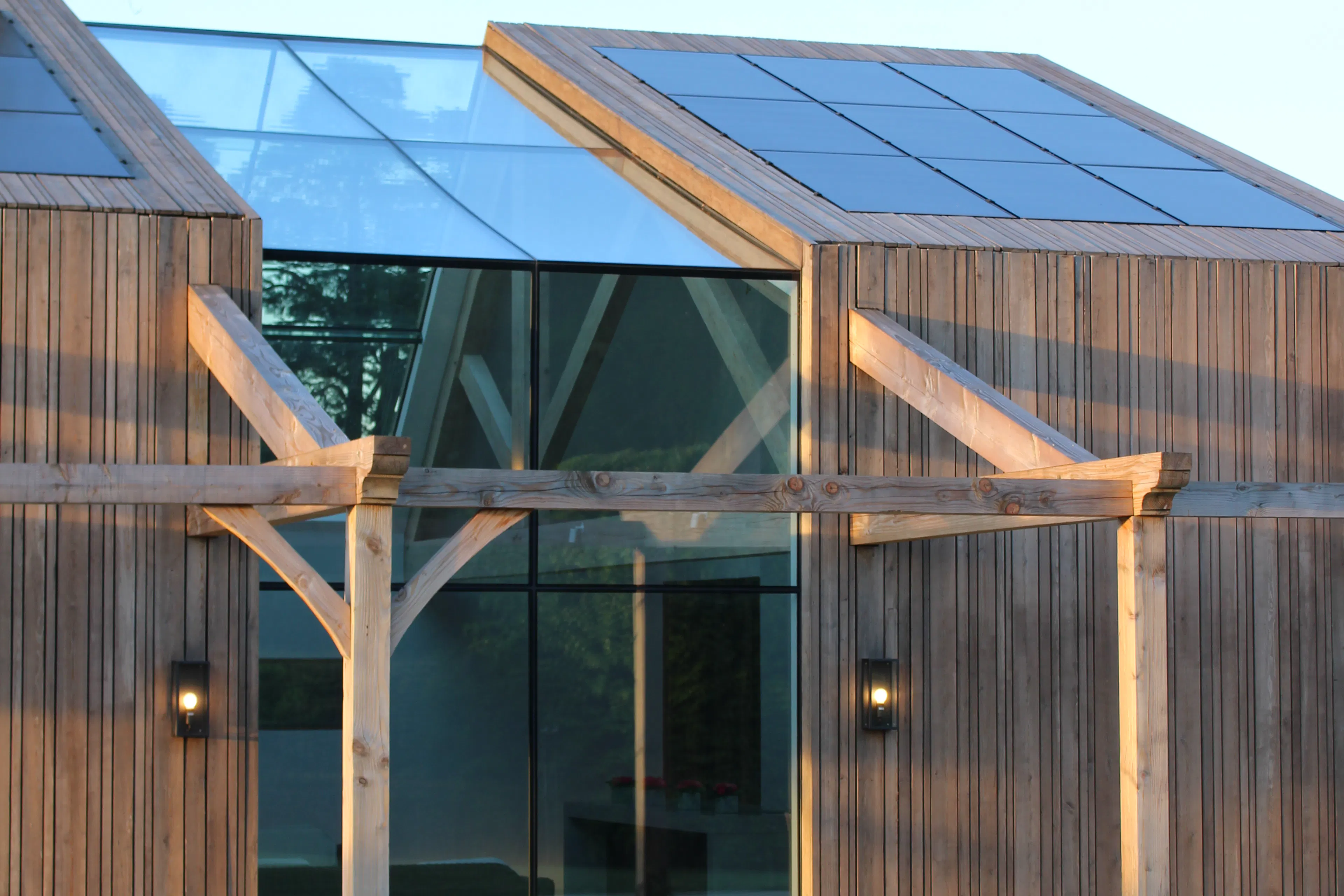 Exterior view of a contemporary glulam-framed pool house featuring full-height glazed panels
