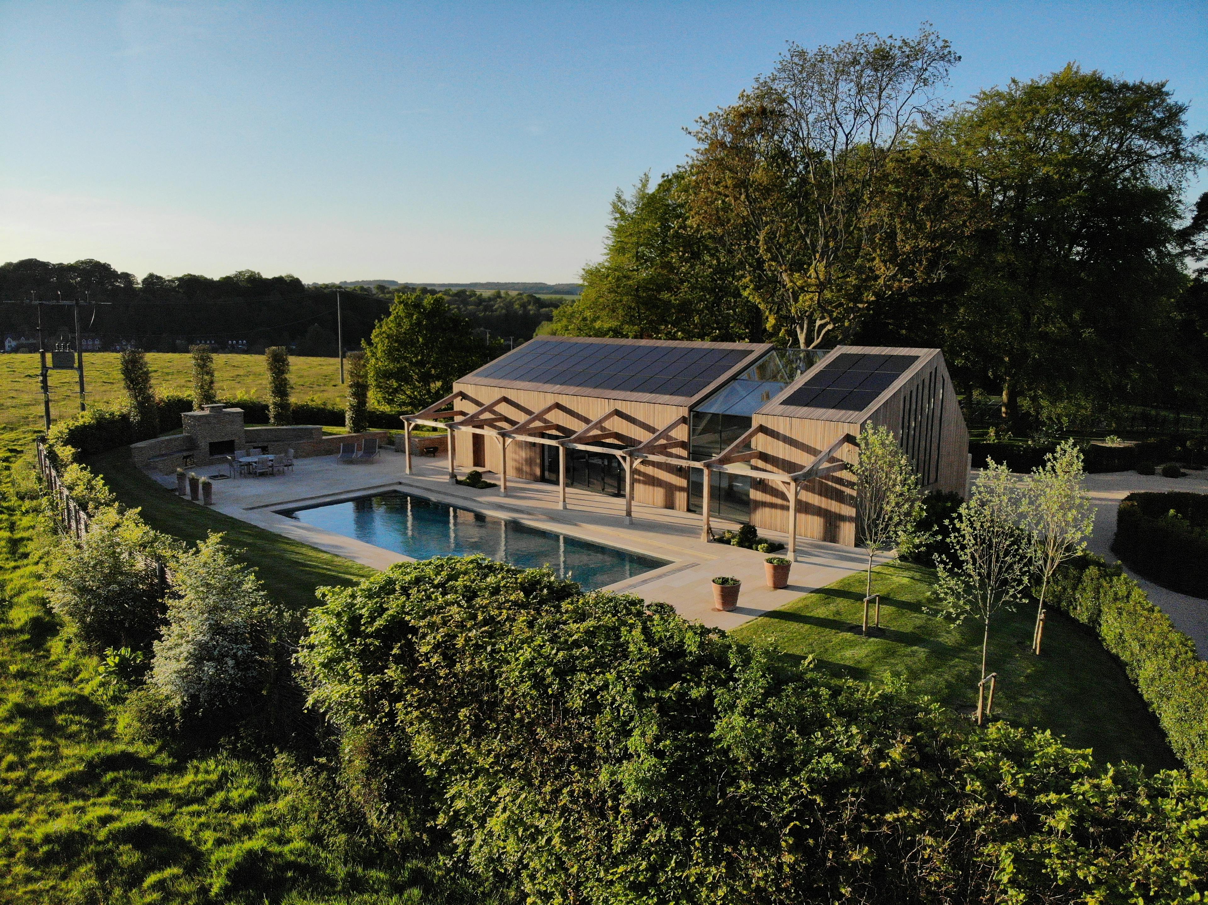 Exterior view of a contemporary swimming pool with a glulam-framed pool house