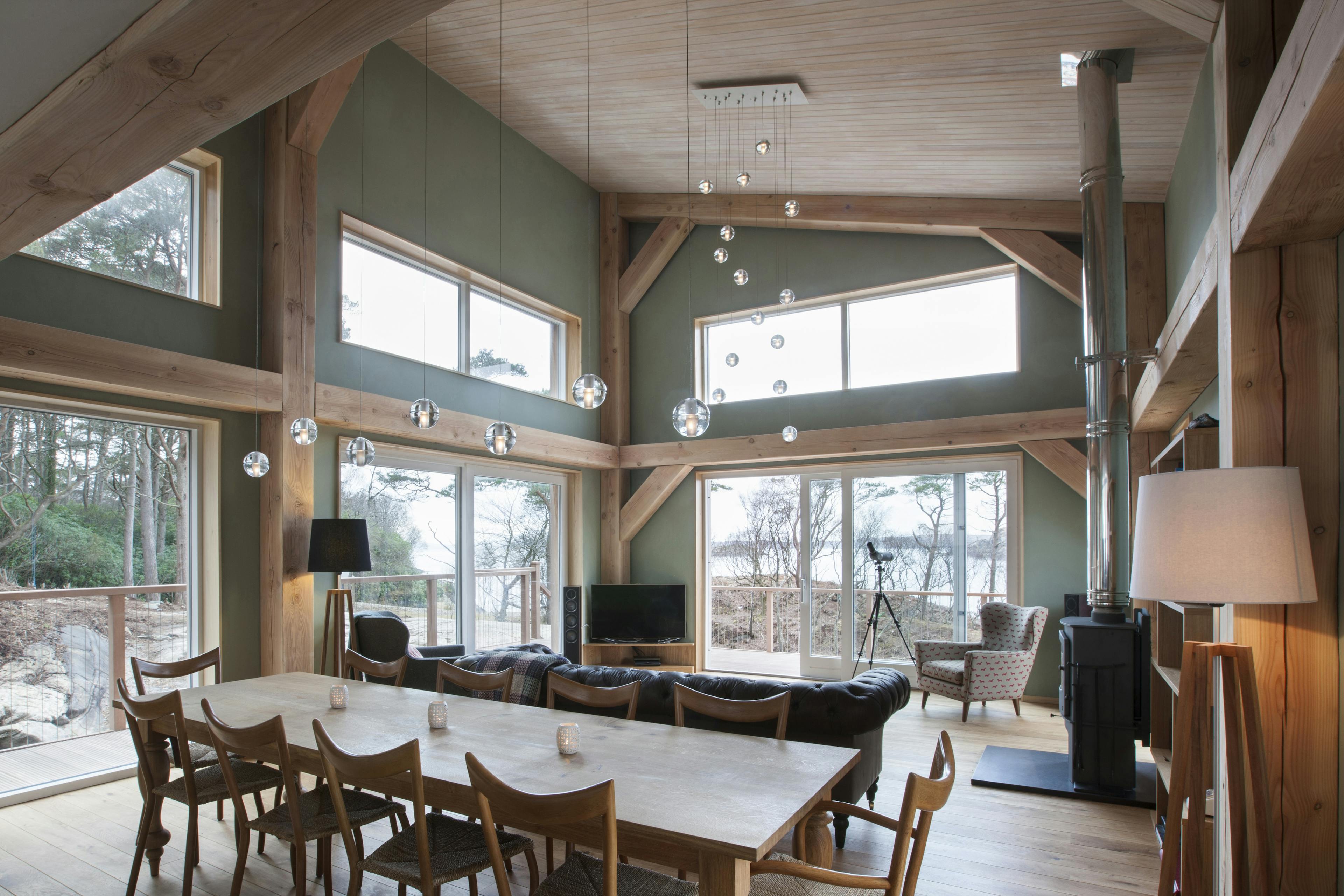 A dining table and sitting area with a log burner in a Douglas fir framed living room with a mono pitch