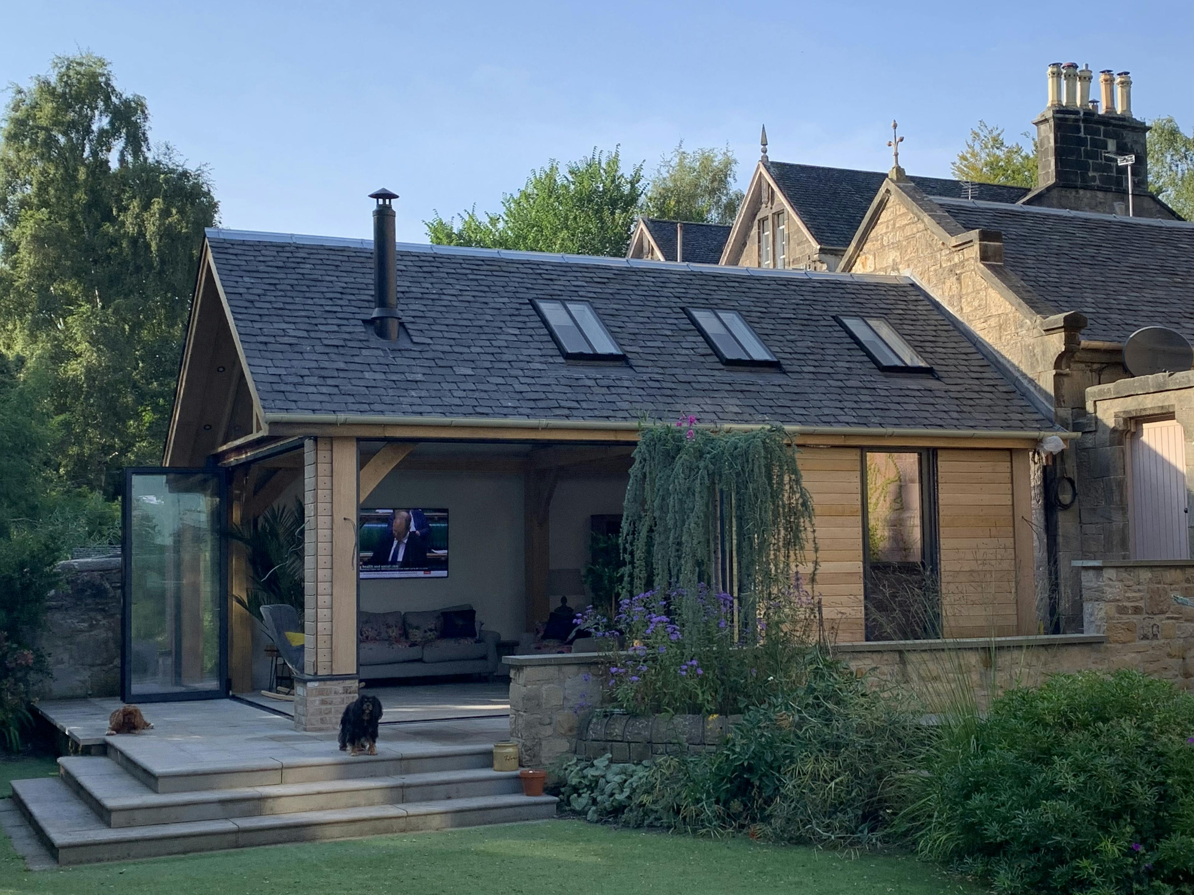 Exterior view of an oak-framed garden room with a fitted kitchen and fireplace
