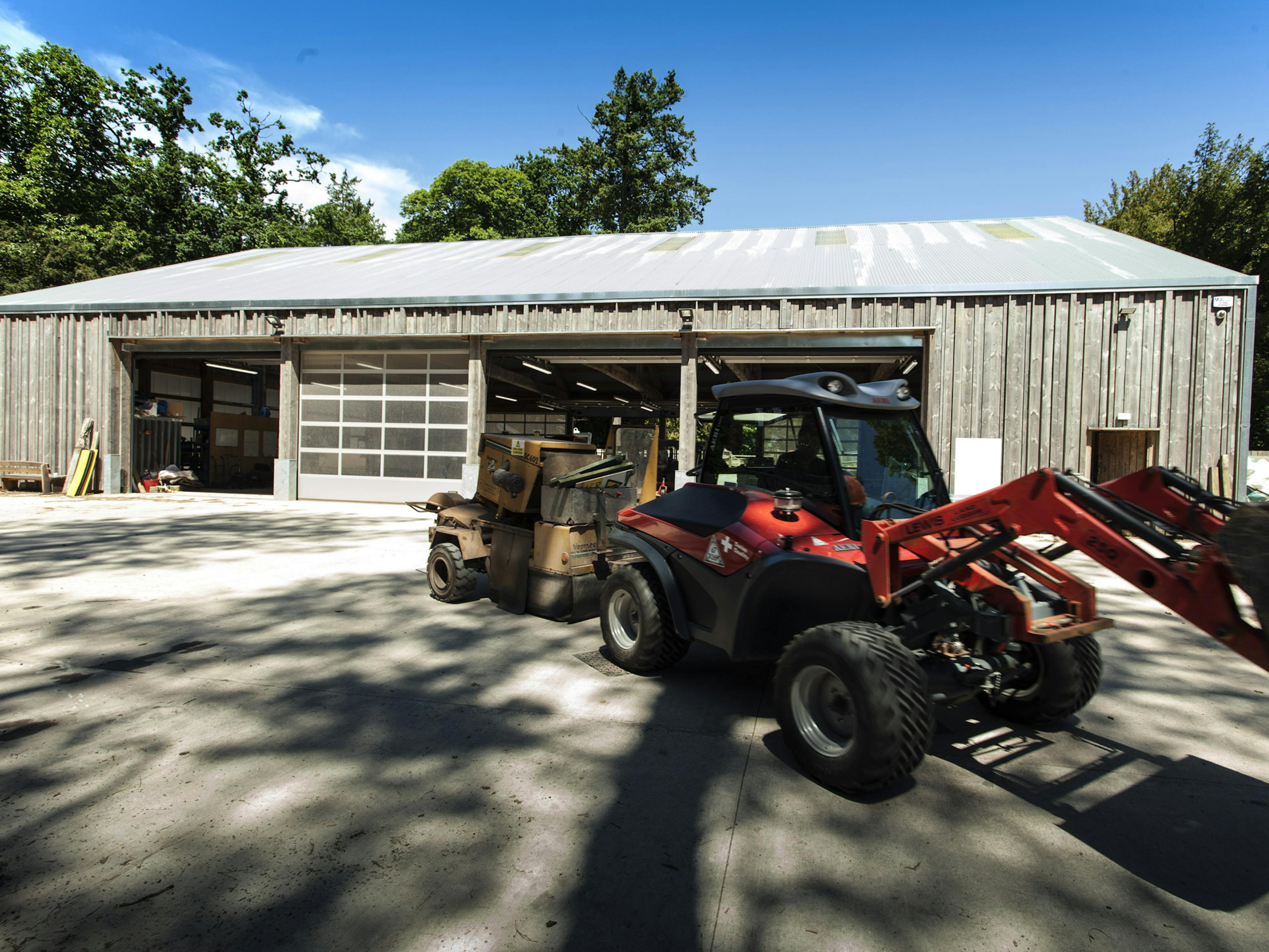 Exterior view of a Douglas fir-framed tractor shed with agricultural vehicles parked outside