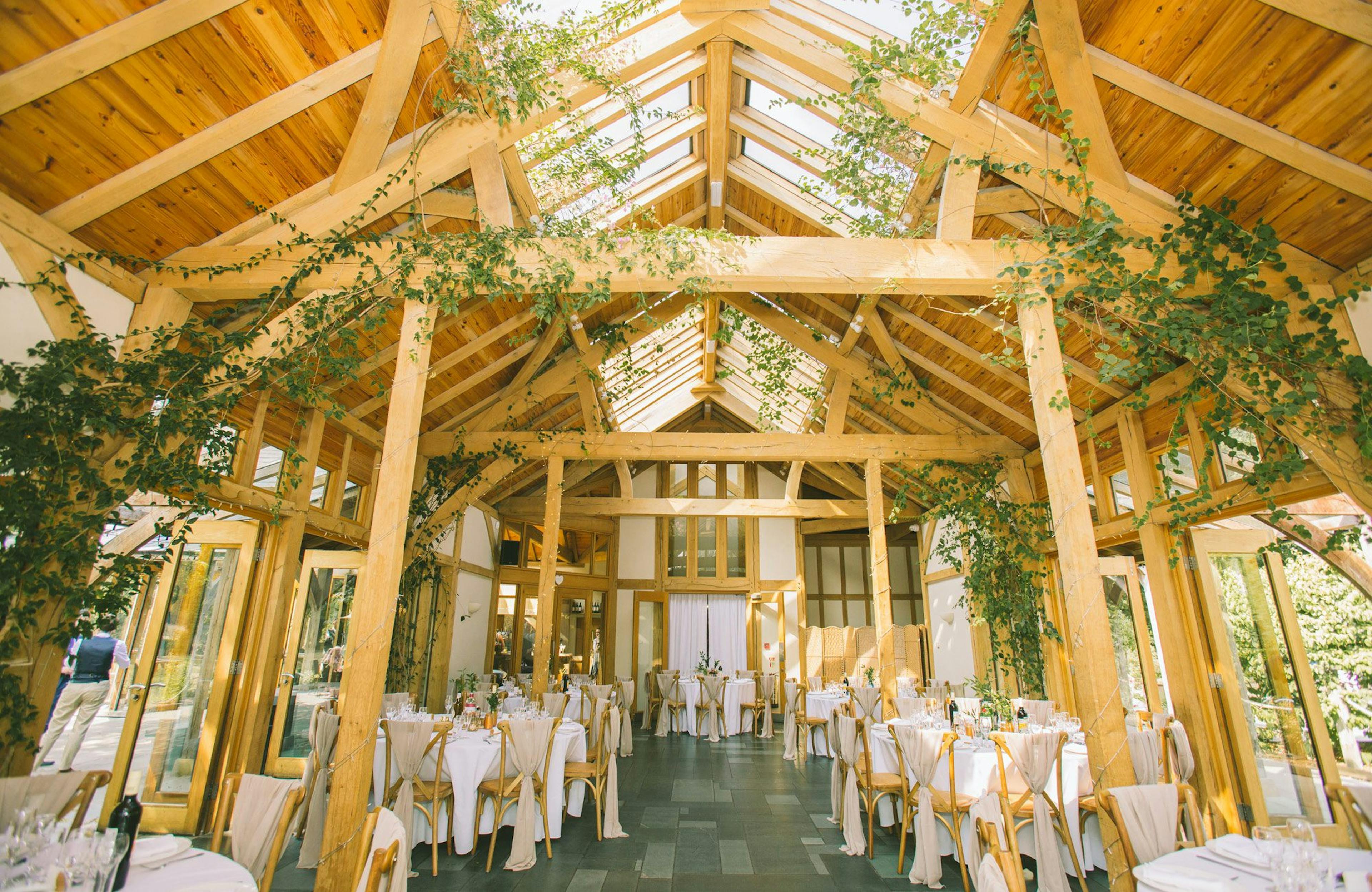Oak-framed wedding barn with rustic decor and climbing plants surrounding the oak trusses