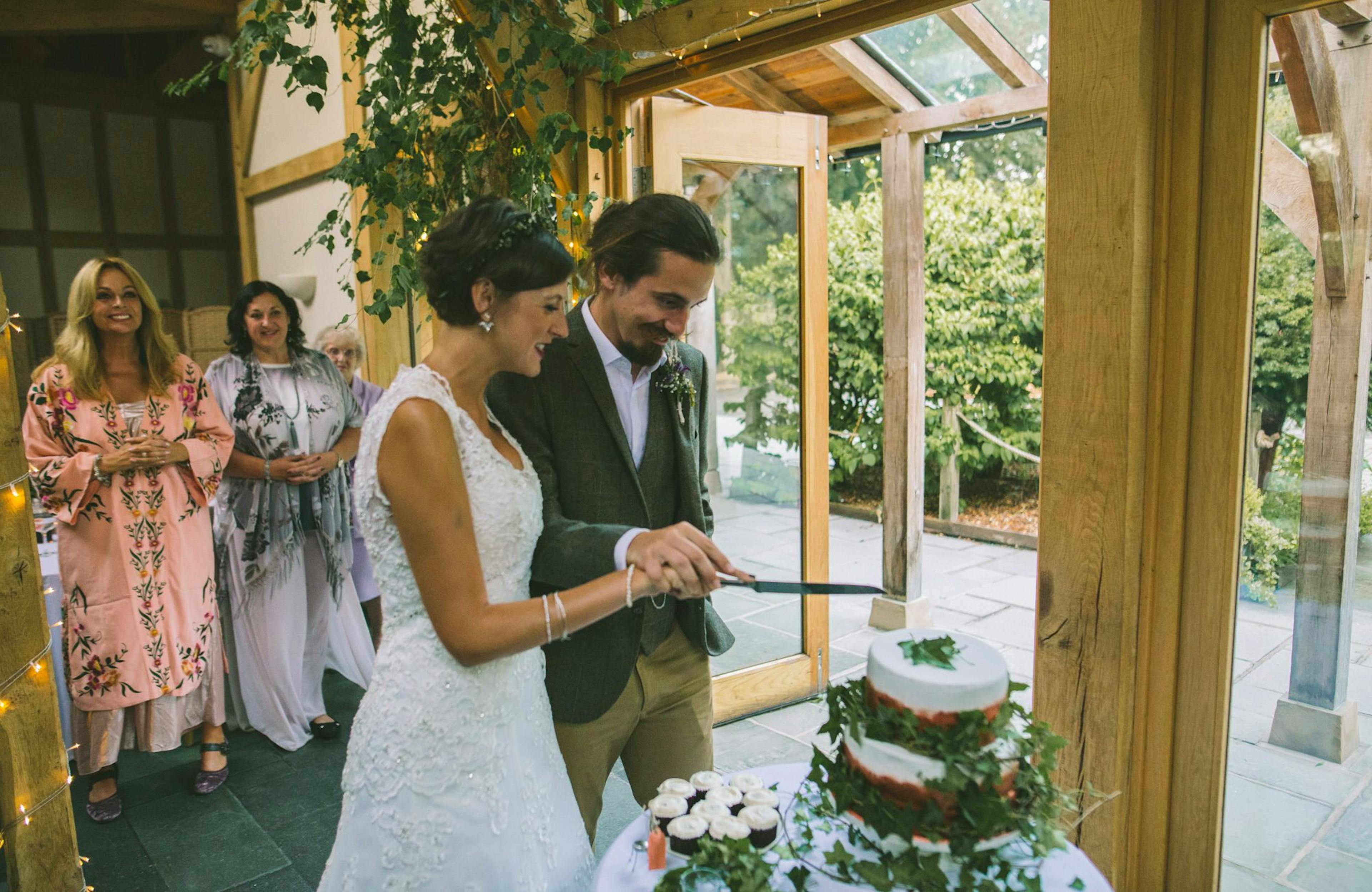 Bride and groom cutting their cake inside a rustic oak-framed wedding barn