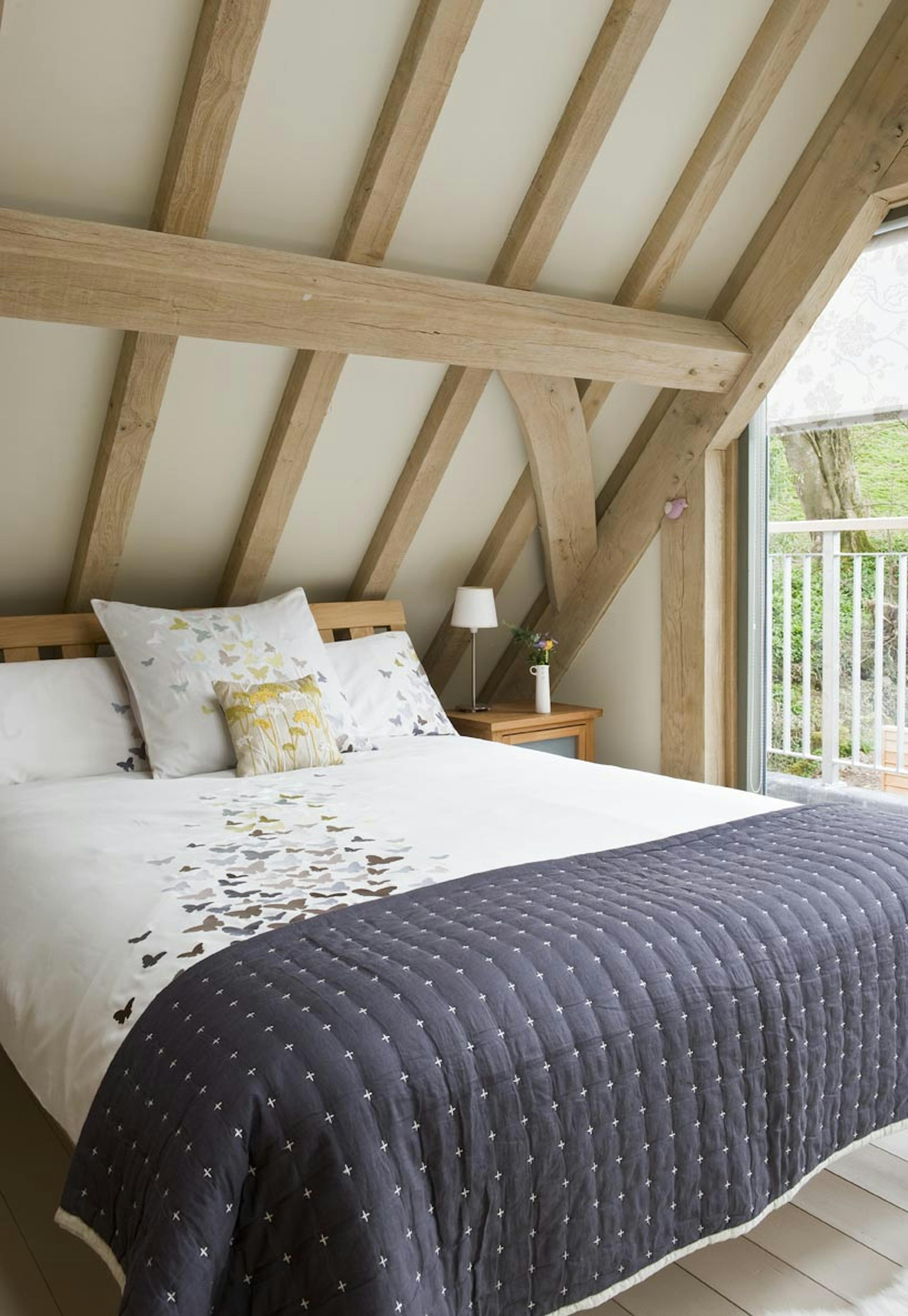 Interior view of an oak-framed bedroom with a balcony offering views across the garden
