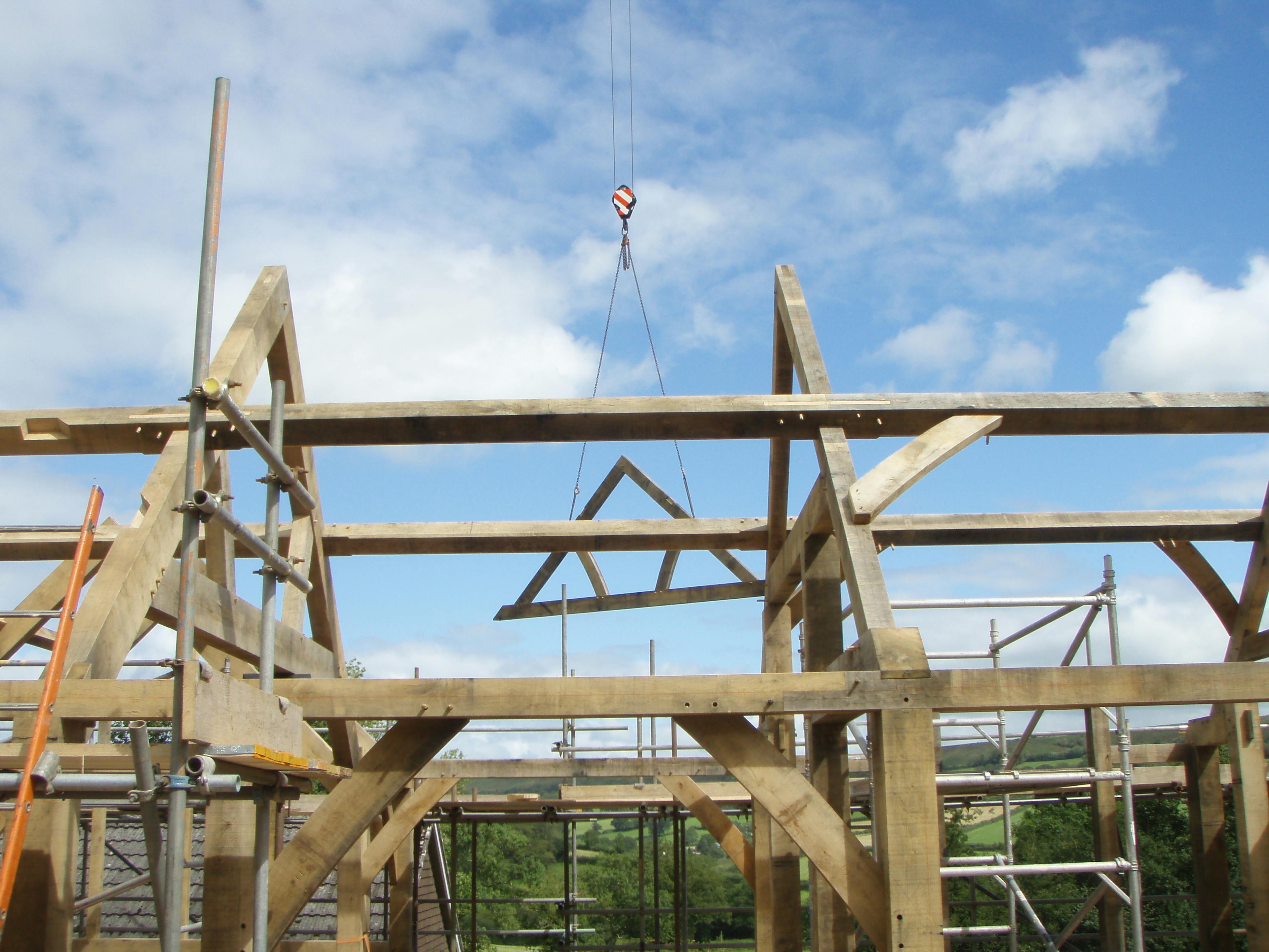 Site installation of a two-storey oak-framed home, lifting a queen post truss into position