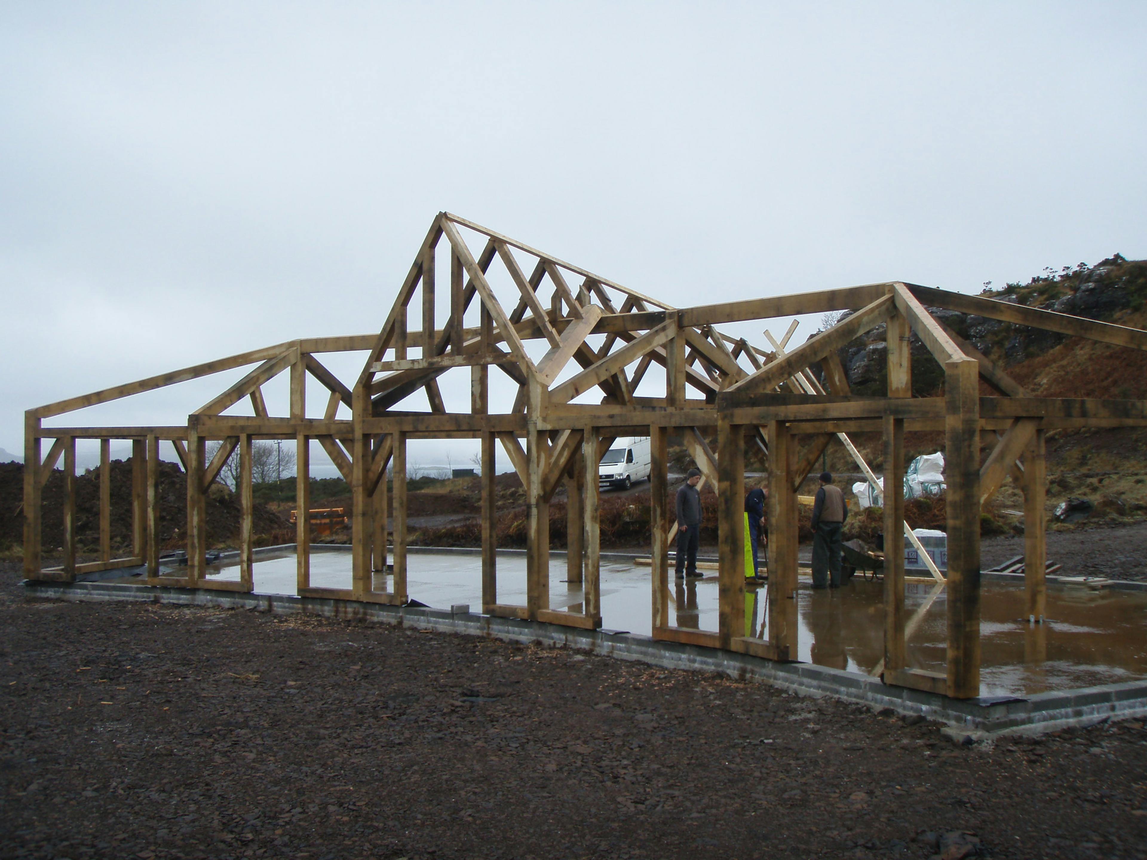 Site installation of a unique, curved oak-framed family home with a pitched central roof lantern