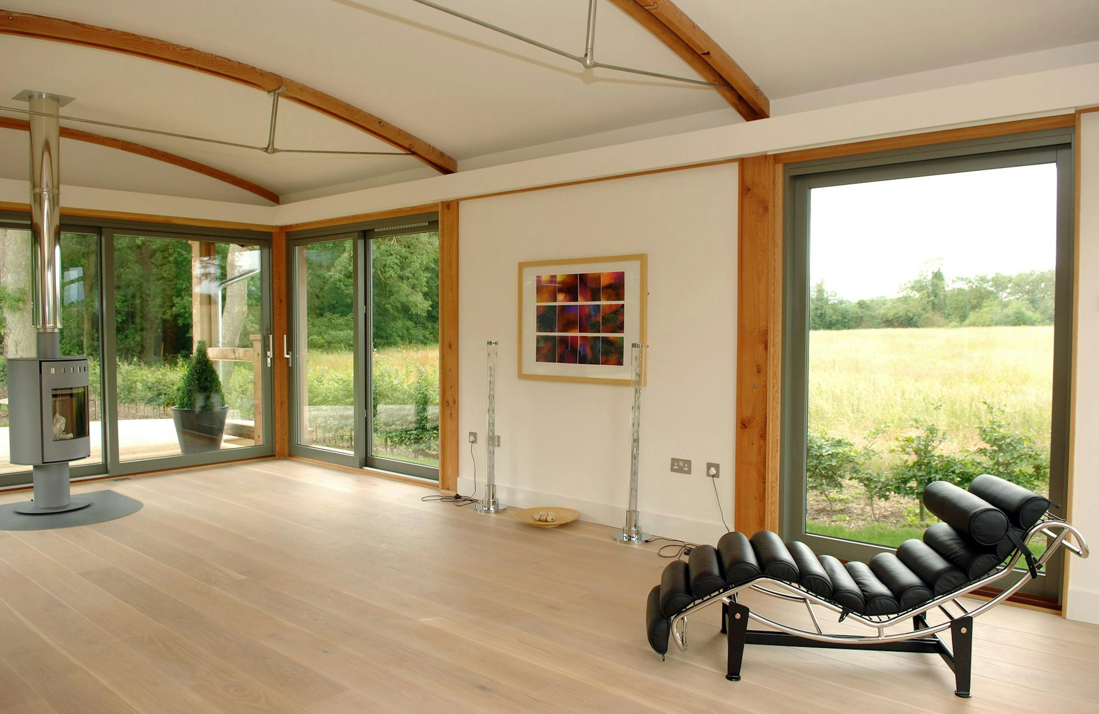 Douglas Fir-Framed Lounge Featuring a Central Log Burner, Curved Trusses with Steel Fixings for a Contemporary Touch