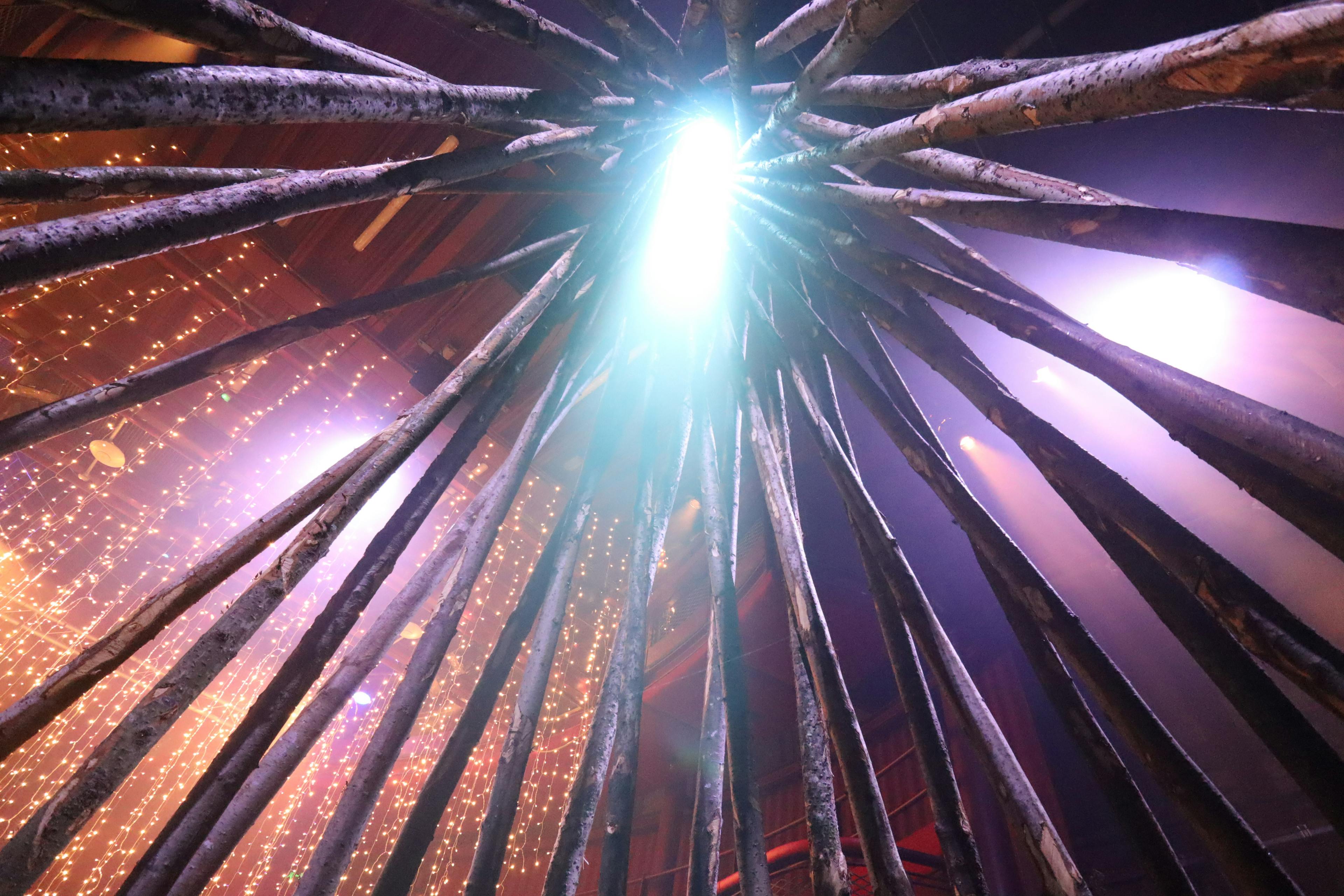 A wooden structure for the forest of imagination festival 2022 with a light shining through it