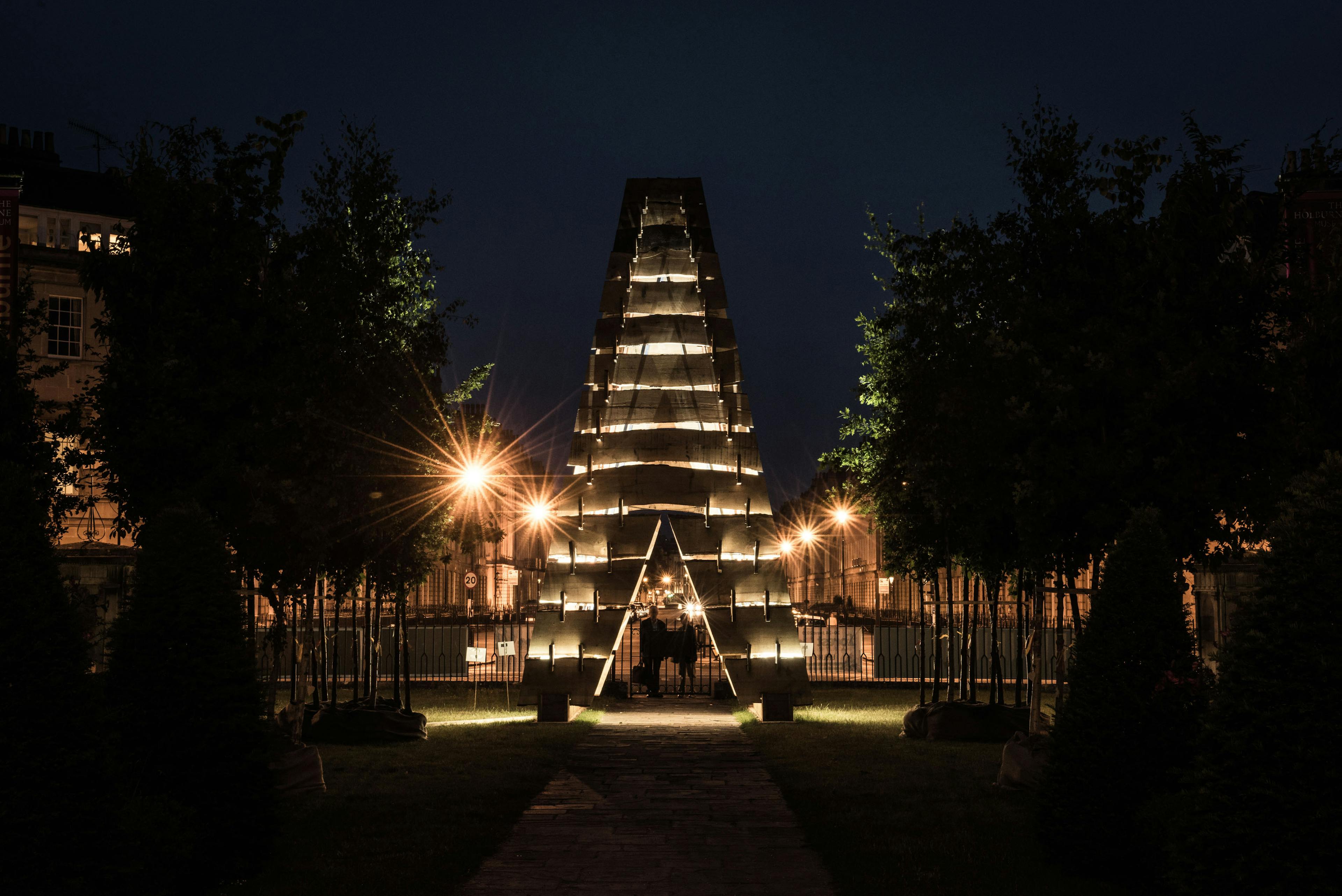A wooden sculpture for the forest of imagination festival in Bath 2019 in the night time with lights shining on it