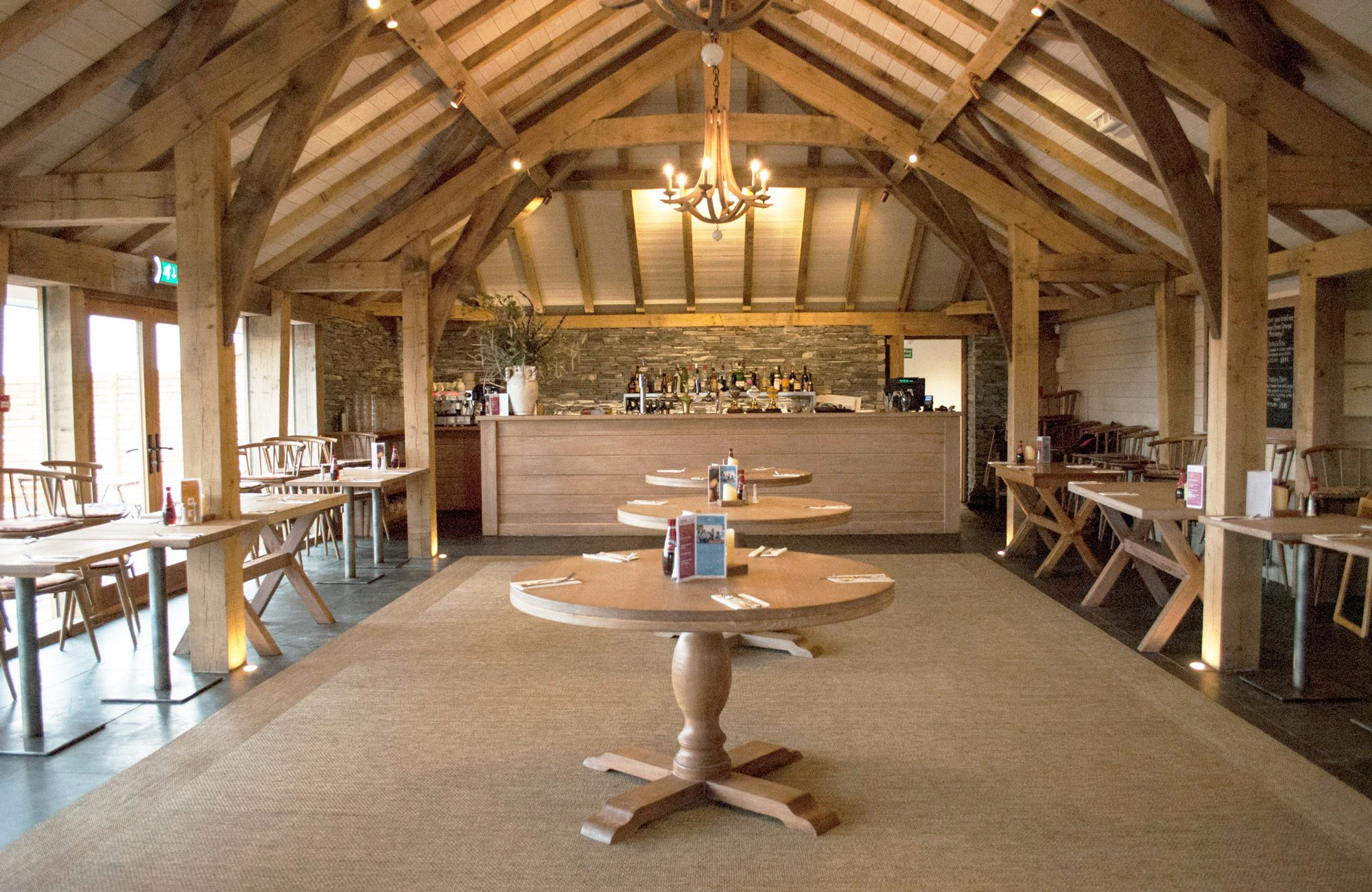 Bar inside Rick Stein's Cornish Arms pub, showcasing a structural oak frame with exposed beams and a warm, inviting atmosphere