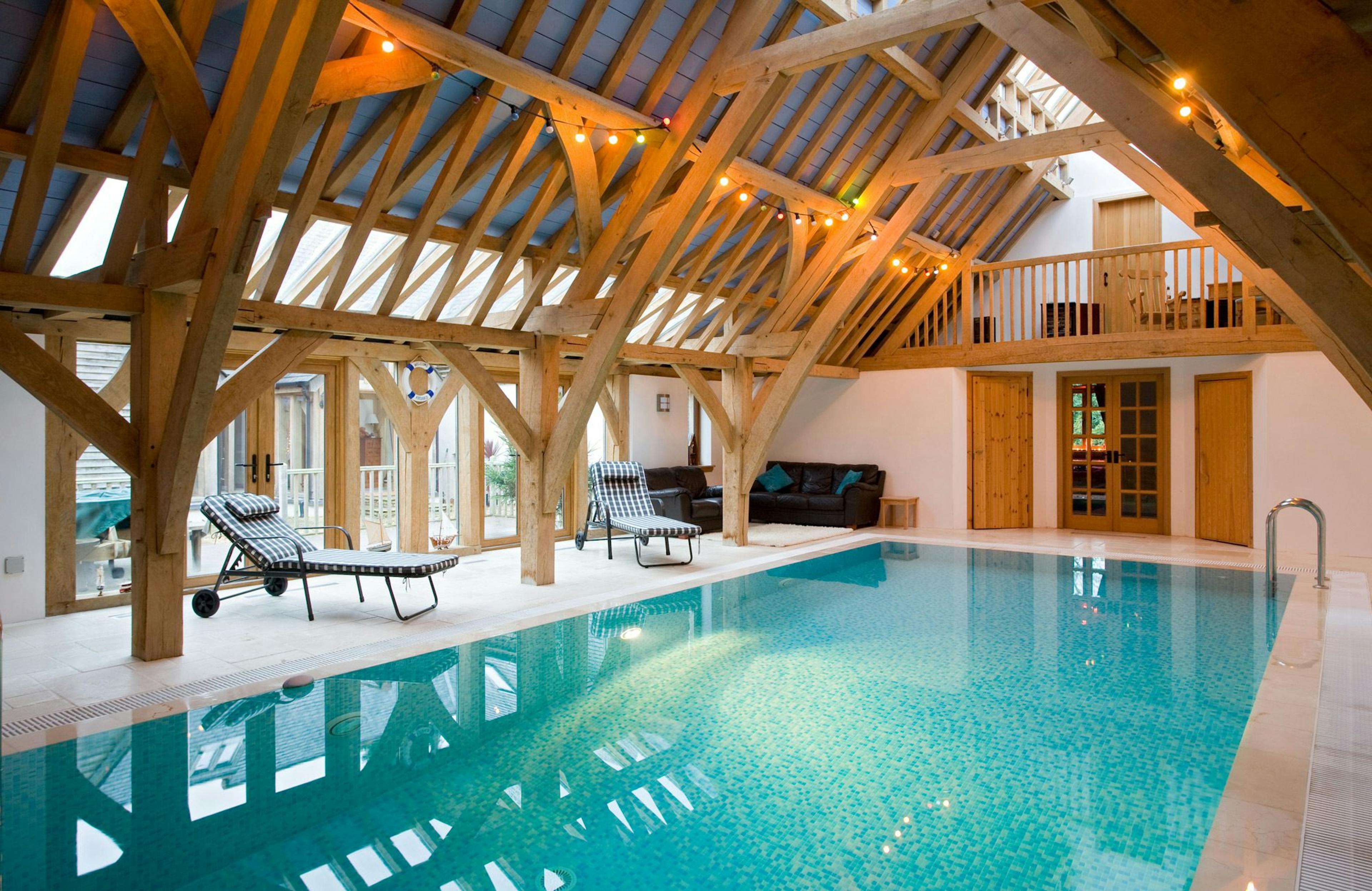 Internal view of a swimming pool enclosed by a structural oak frame, featuring a mezzanine