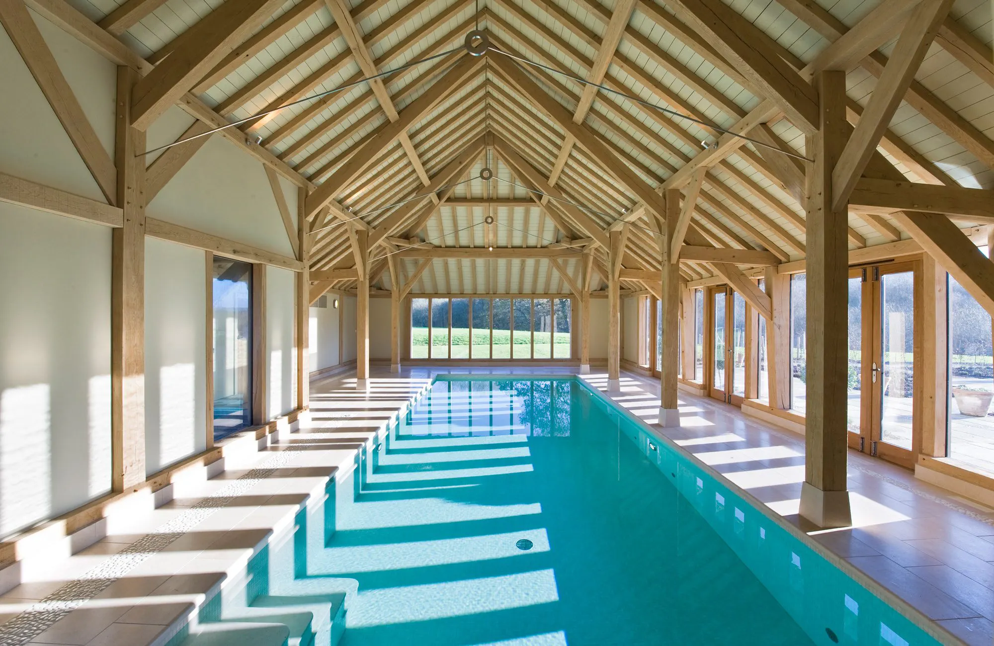 Internal view of a swimming pool enclosed by a structural timber frame with sleek stainless steel connections