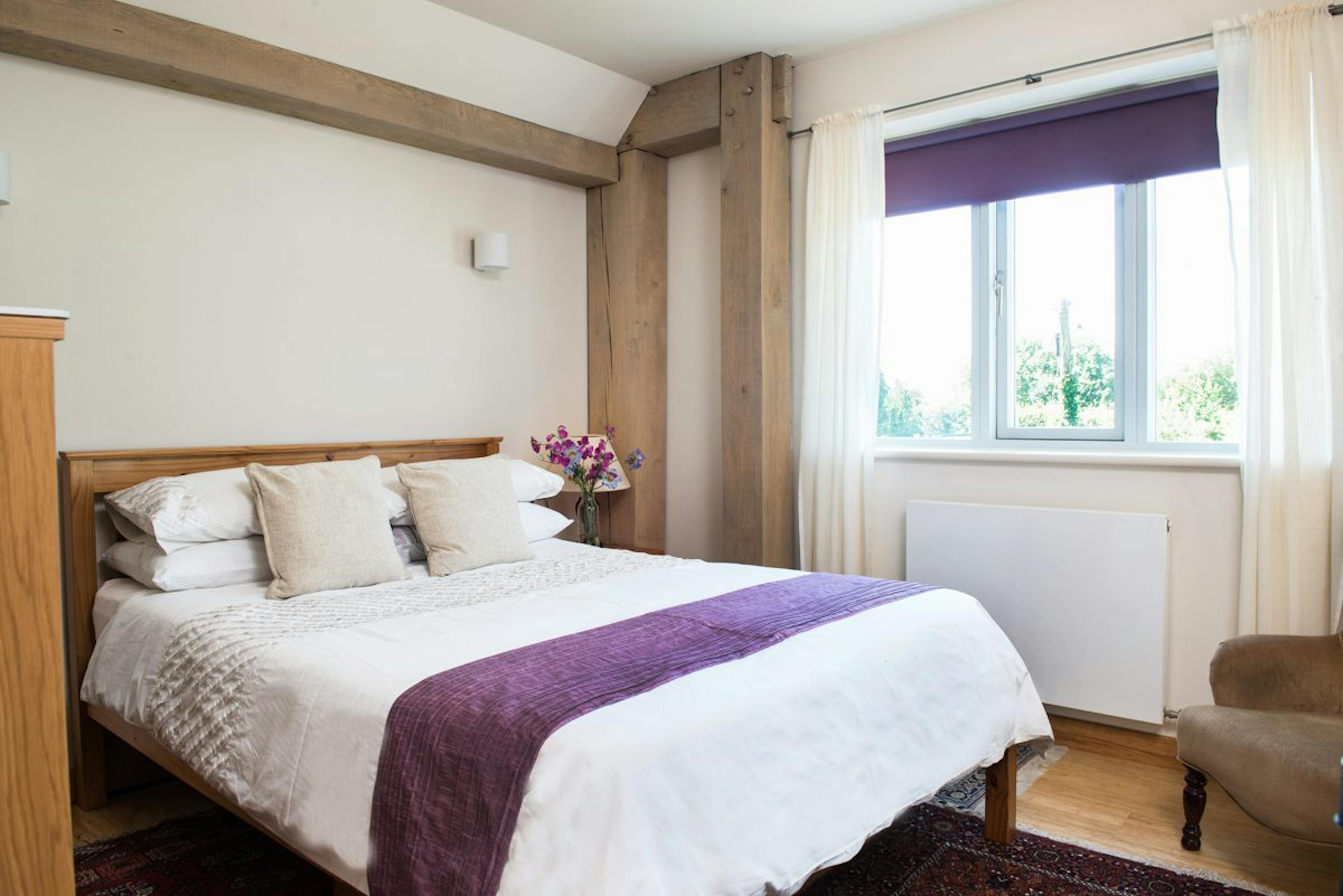 Internal view of a cosy bedroom featuring exposed beams within a structural timber-framed family home