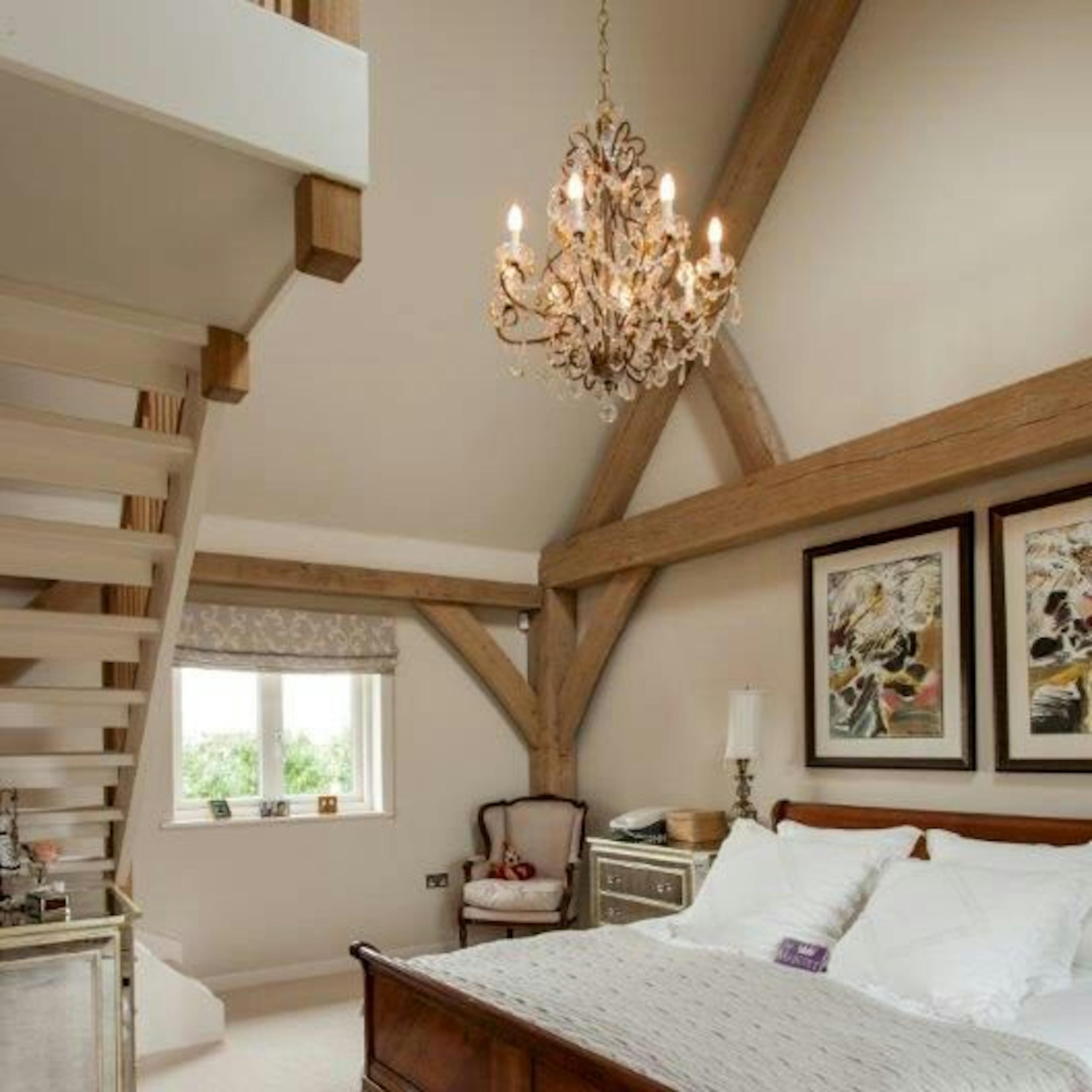 A vaulted bedroom within an oak-framed family home, featuring a built-in staircase leading to a wardrobe area