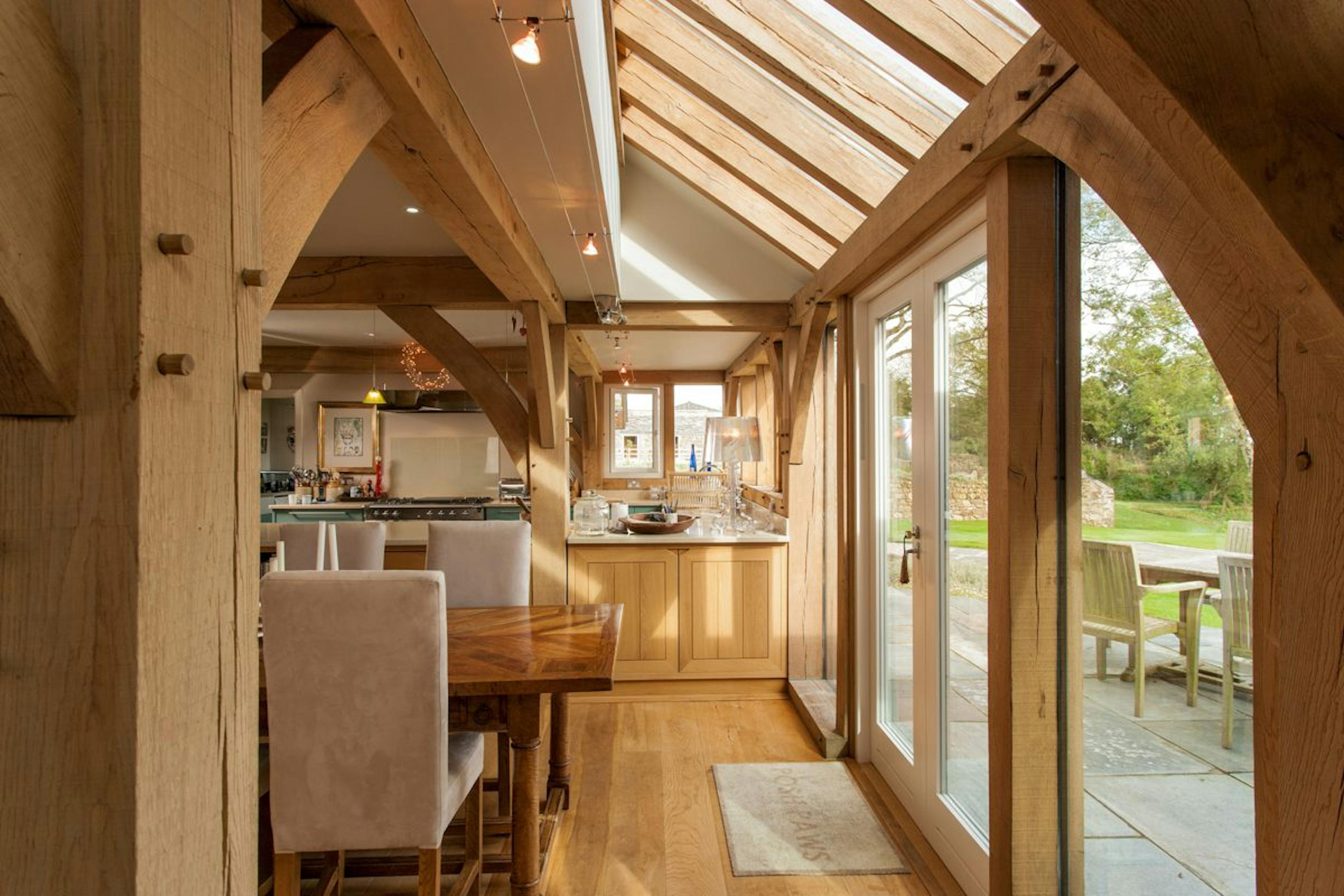 An oak-framed lean-to structure integrated into a timber frame, featuring roof lanterns that enhance the open-plan space with natural light