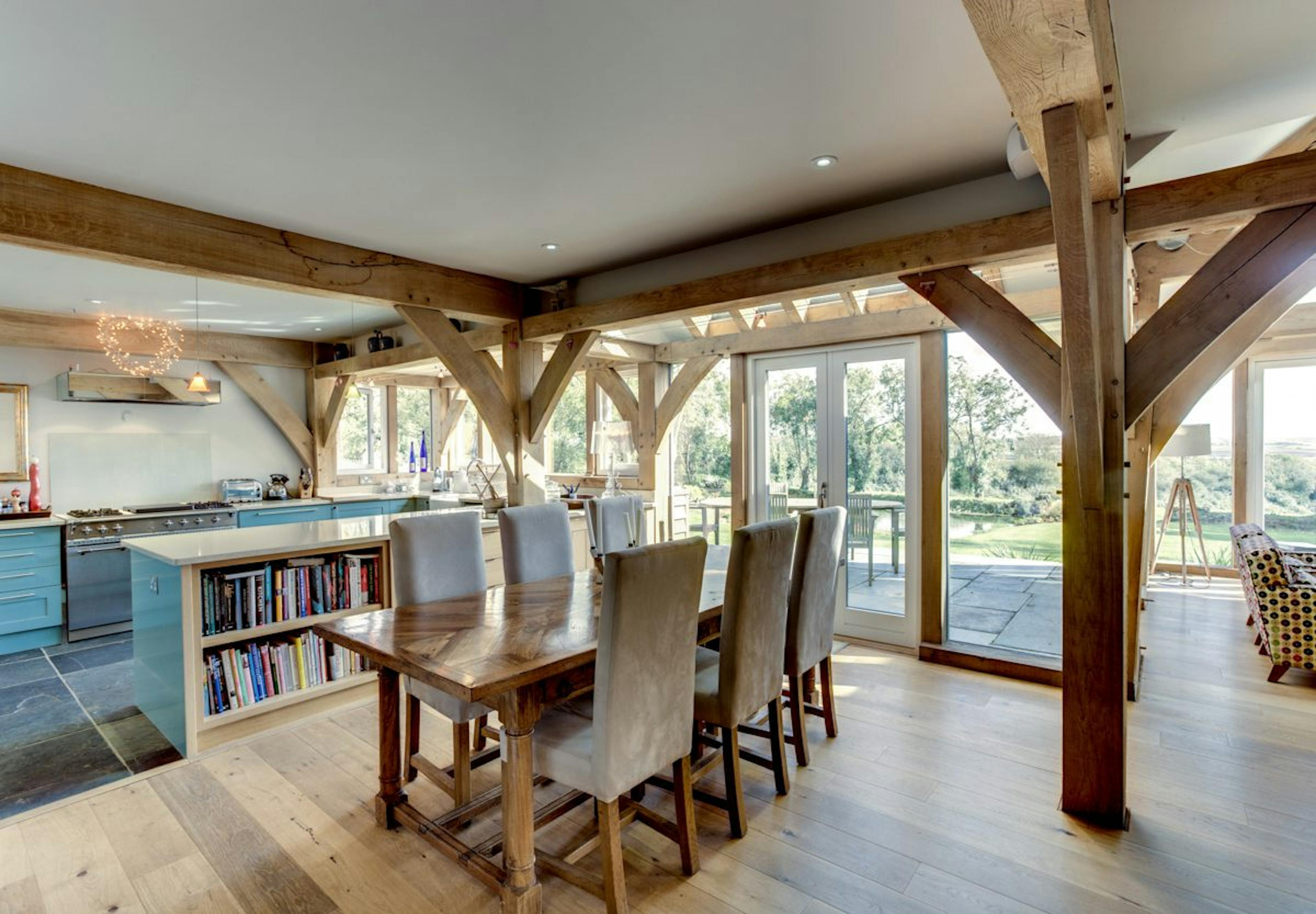 A farmhouse kitchen featuring a Cornish oak frame, highlighting rustic charm with wooden beams and a cosy, traditional design