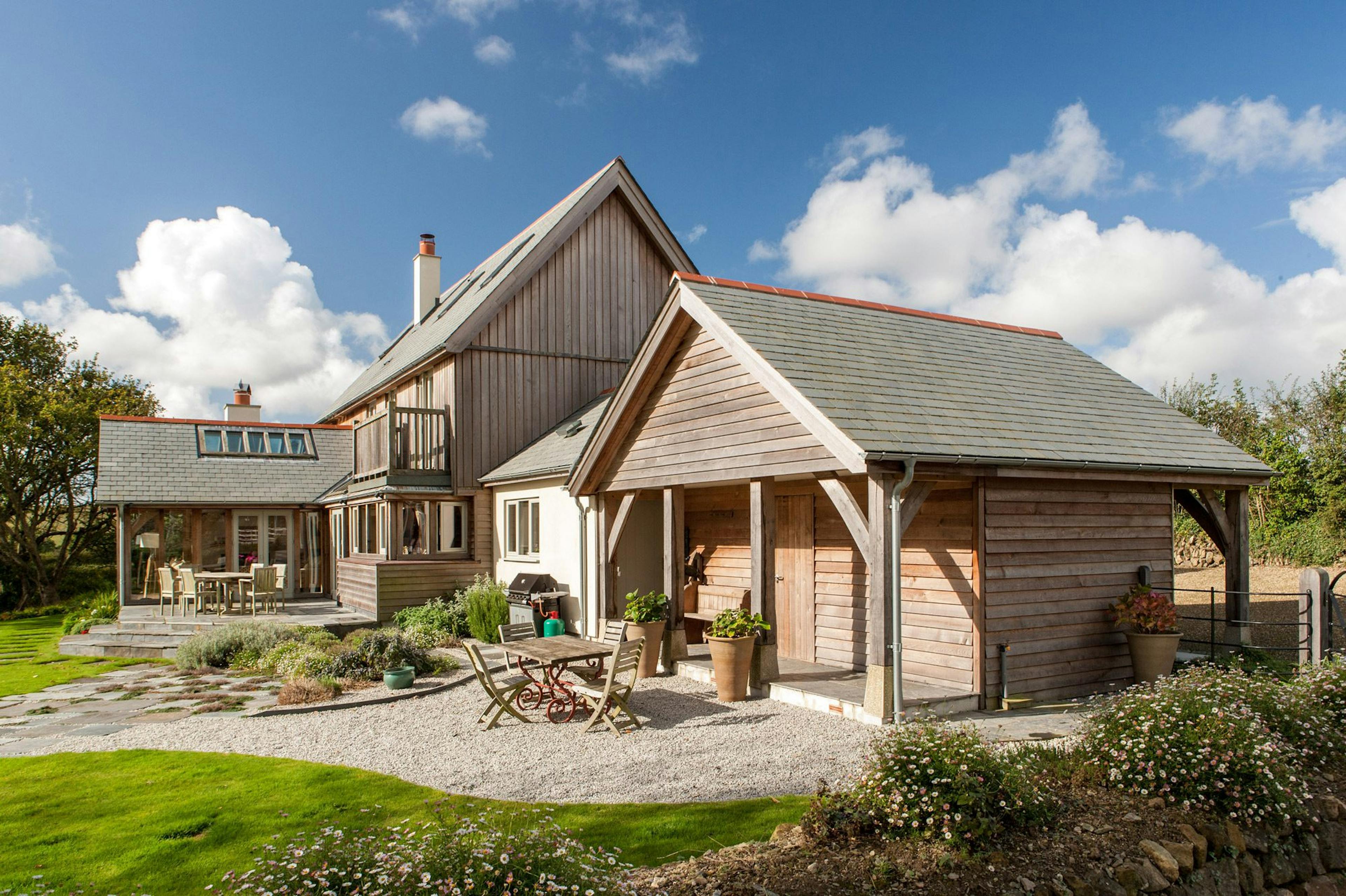A rustic oak-framed family home with timber cladding, nestled in the countryside, blending natural beauty and rural charm