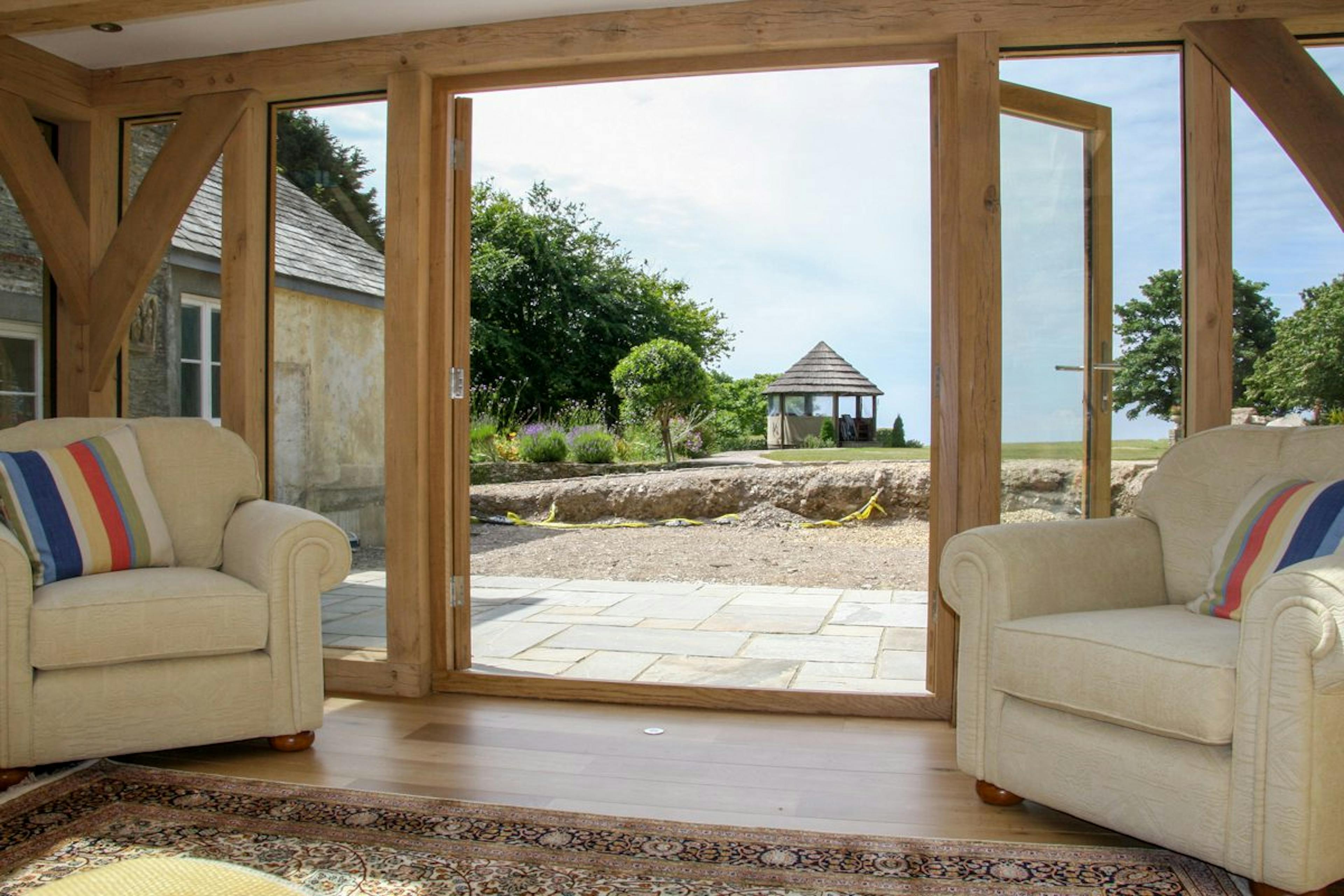 An oak-framed extension in Devon with large glass panels, offering a clear view of a beautifully landscaped garden
